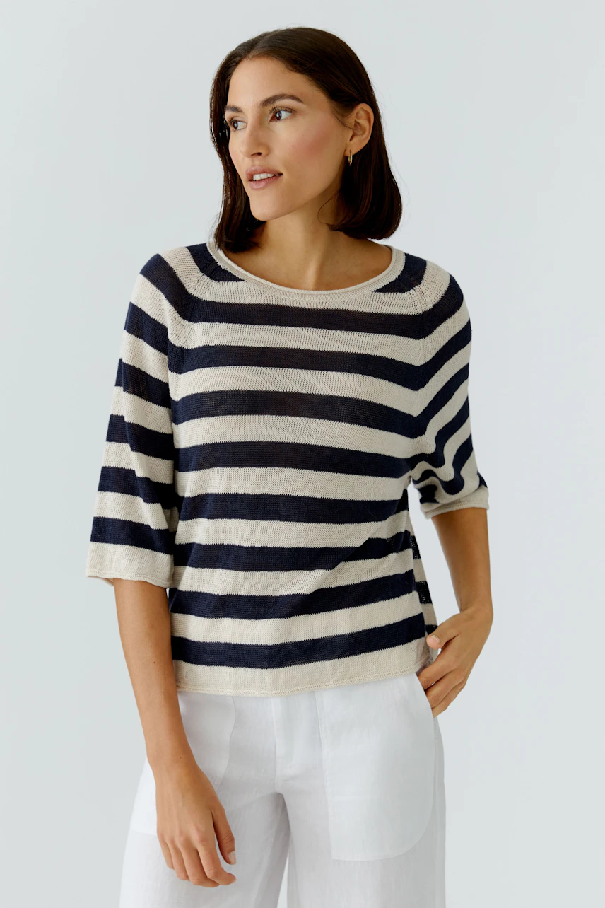 Casual women's pullover: Young woman in a striped pullover with three-quarter sleeves, paired with light trousers.