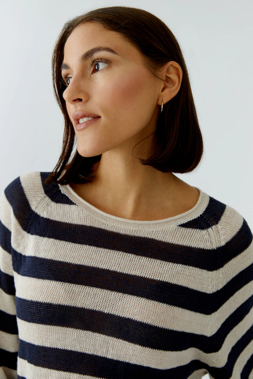 Casual women's pullover: Young woman in a striped pullover with a relaxed fit, smiling softly.