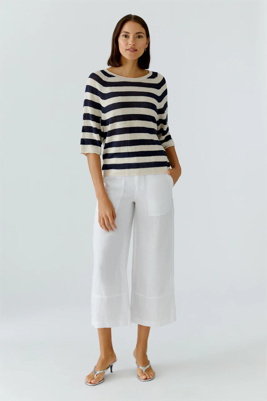 Casual women's pullover: A woman in a striped pullover with three-quarter sleeves and white pants.