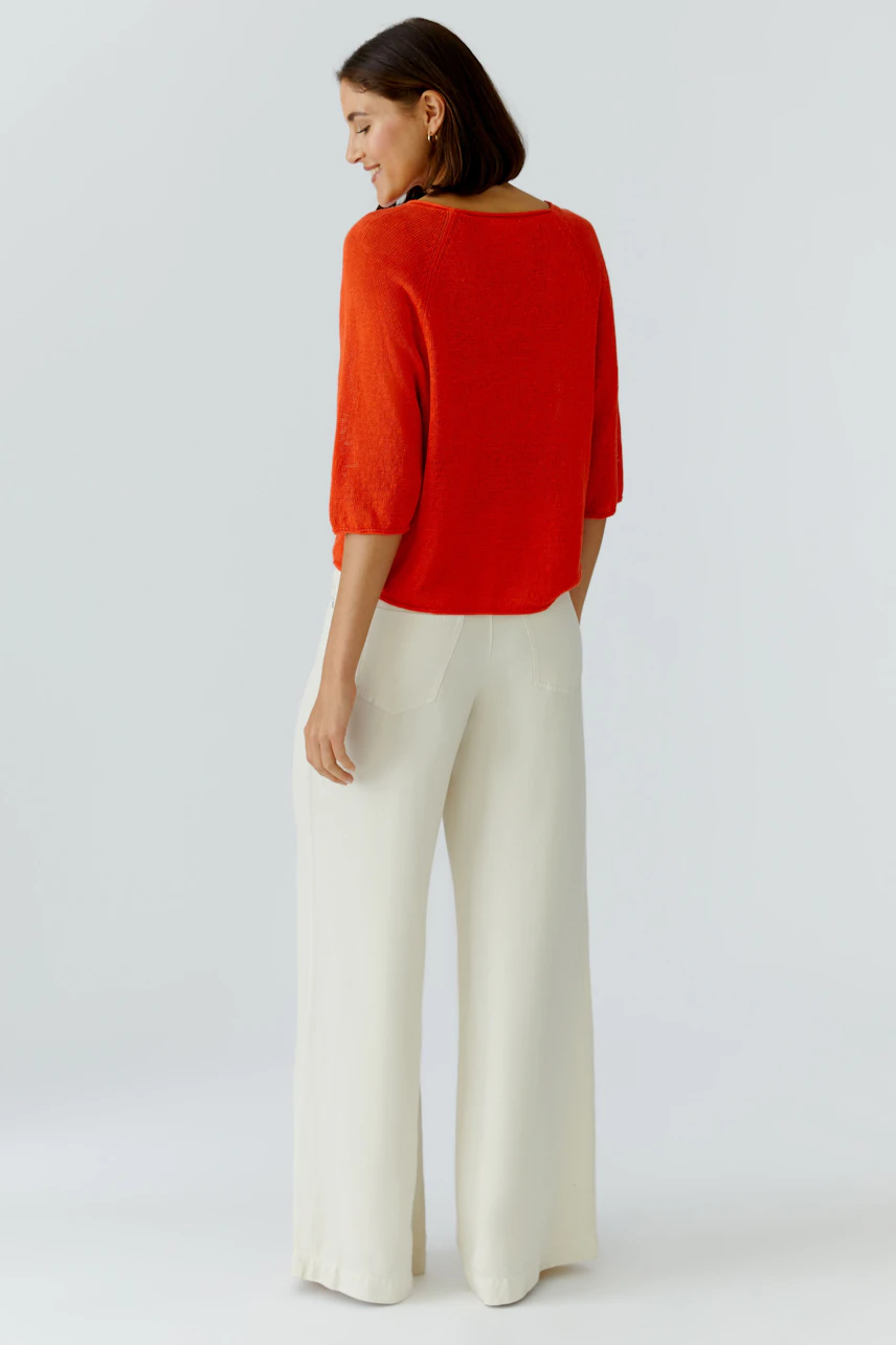 Casual women's pullover: A woman in a vibrant red pullover with three-quarter sleeves, paired with wide trousers.