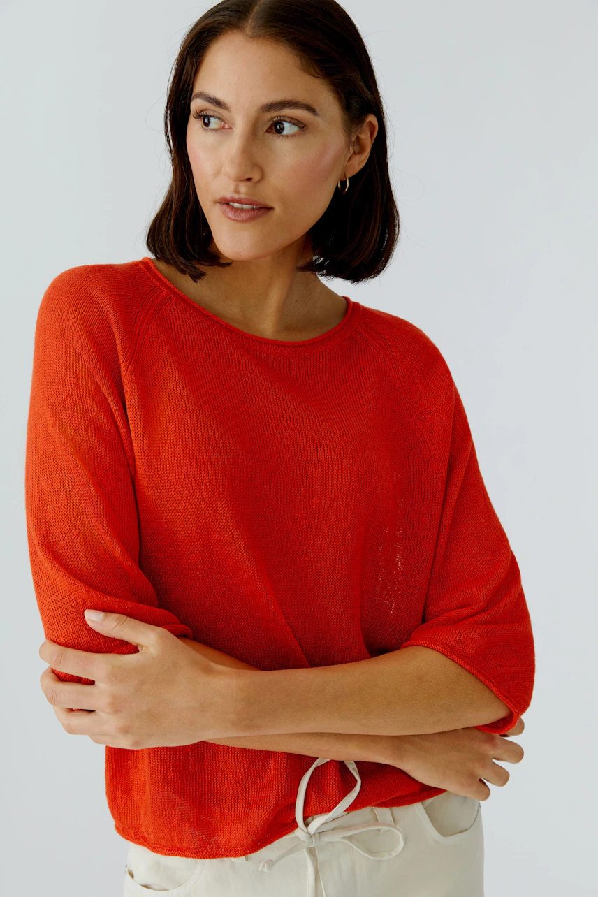 Casual women's pullover: A woman in a vibrant red pullover with relaxed sleeves, looking thoughtfully.