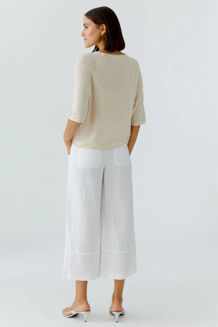 Casual women's pullover: A woman in a light beige pullover with three-quarter sleeves, paired with wide white pants.