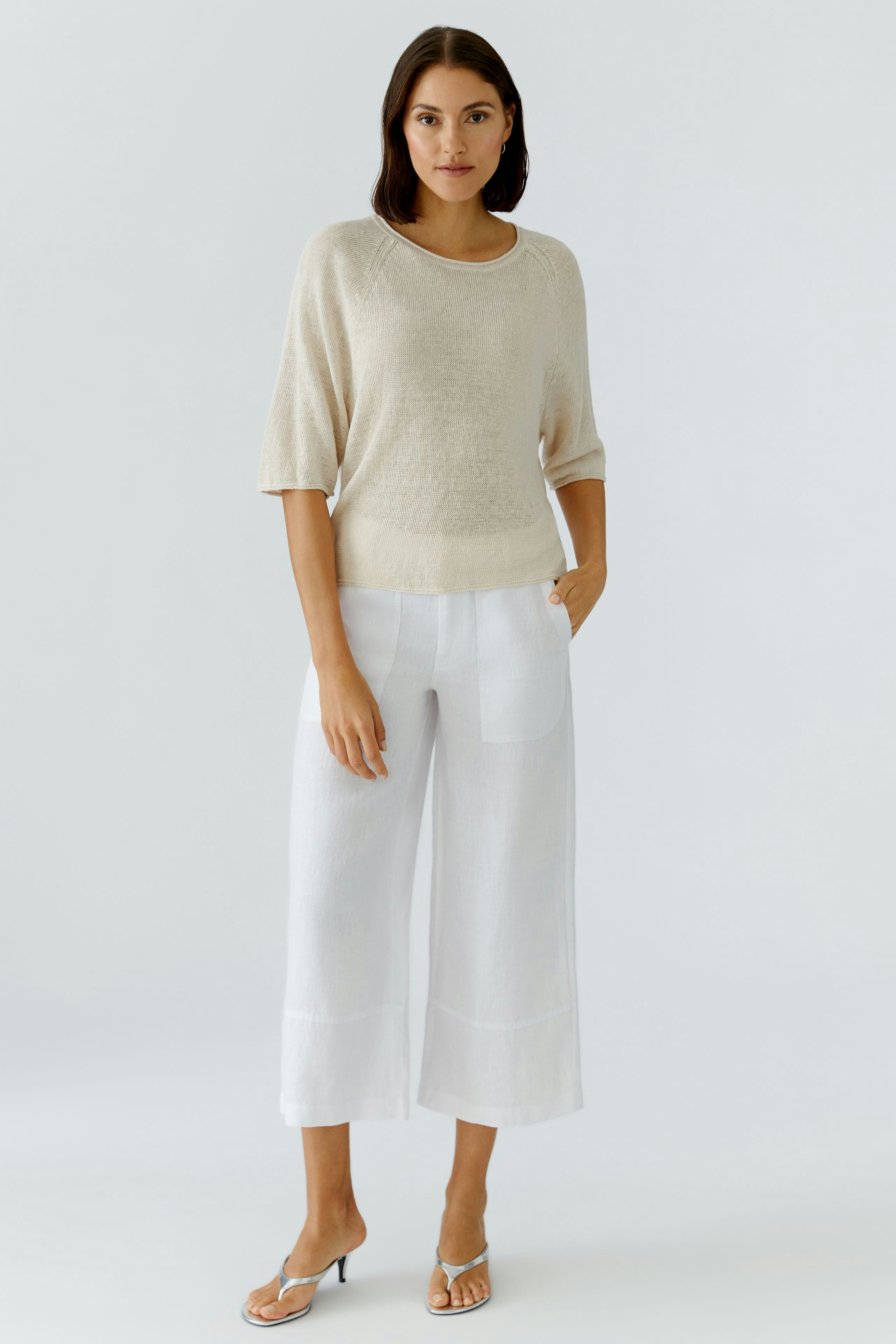 Bequemer Damen-Pullover in hellem Beige, lässig kombiniert mit weißen Hosen, Model mit natürlichem Look.
