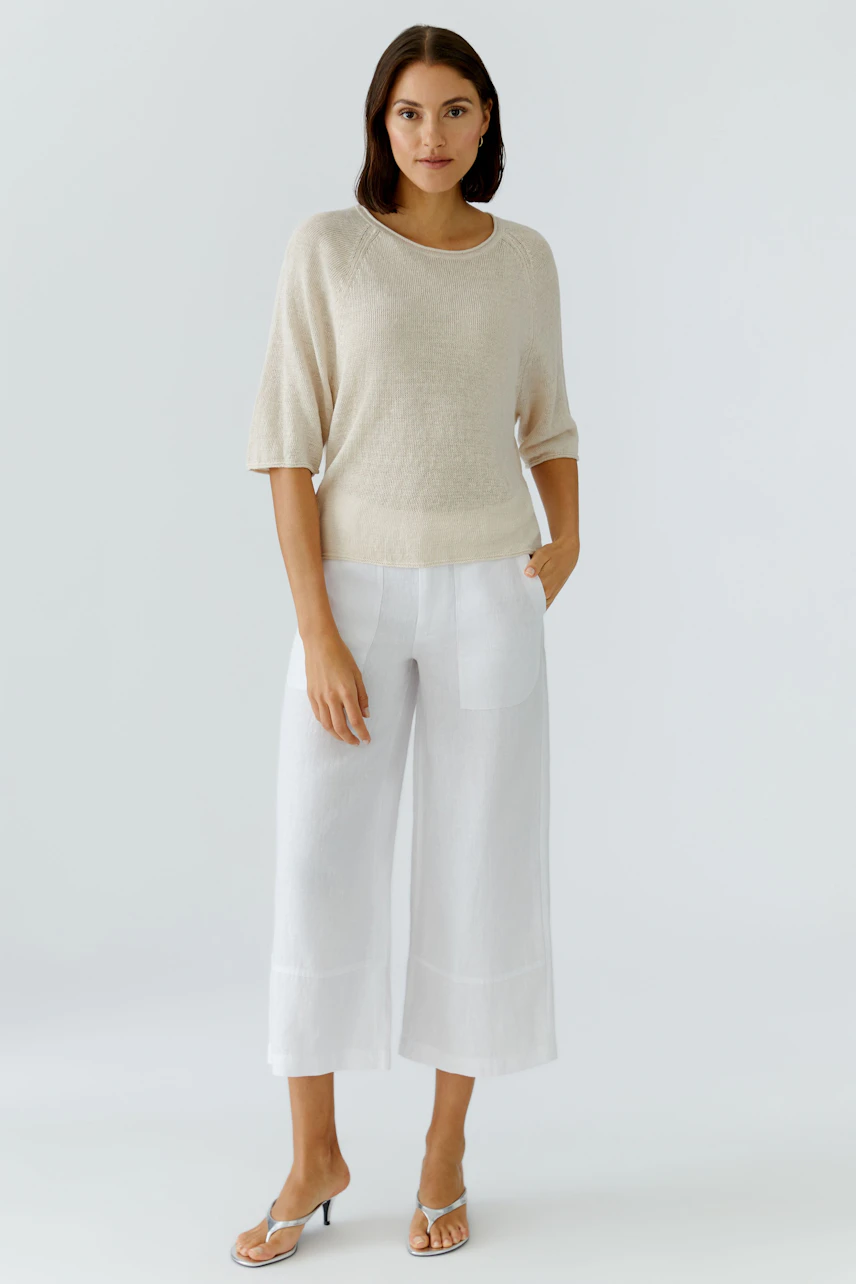 Casual women's pullover: A woman in a light beige pullover paired with white wide-leg pants.