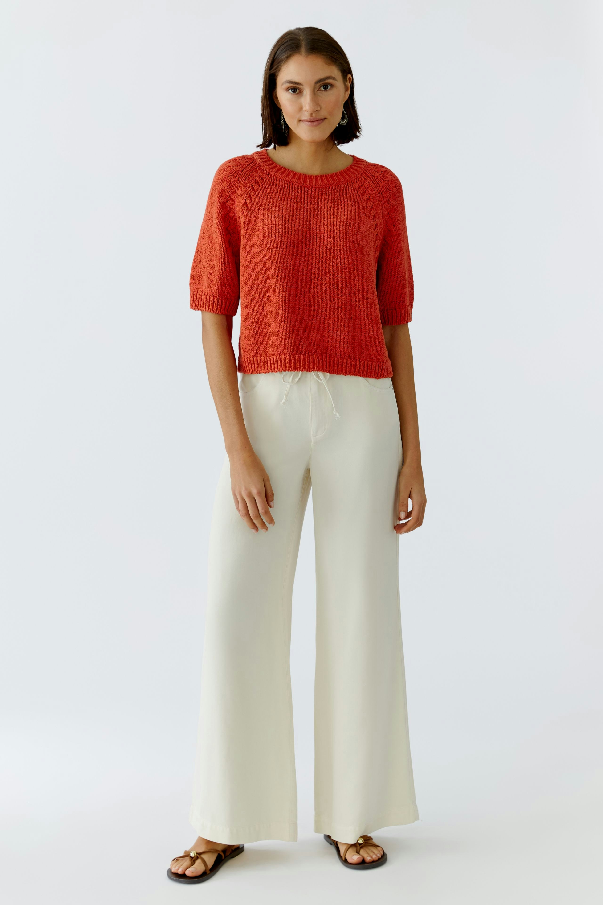 Damen-Pullover: Junge Frau trägt einen roten, lässigen Pullover mit kurzen Ärmeln und weiten Hosen.