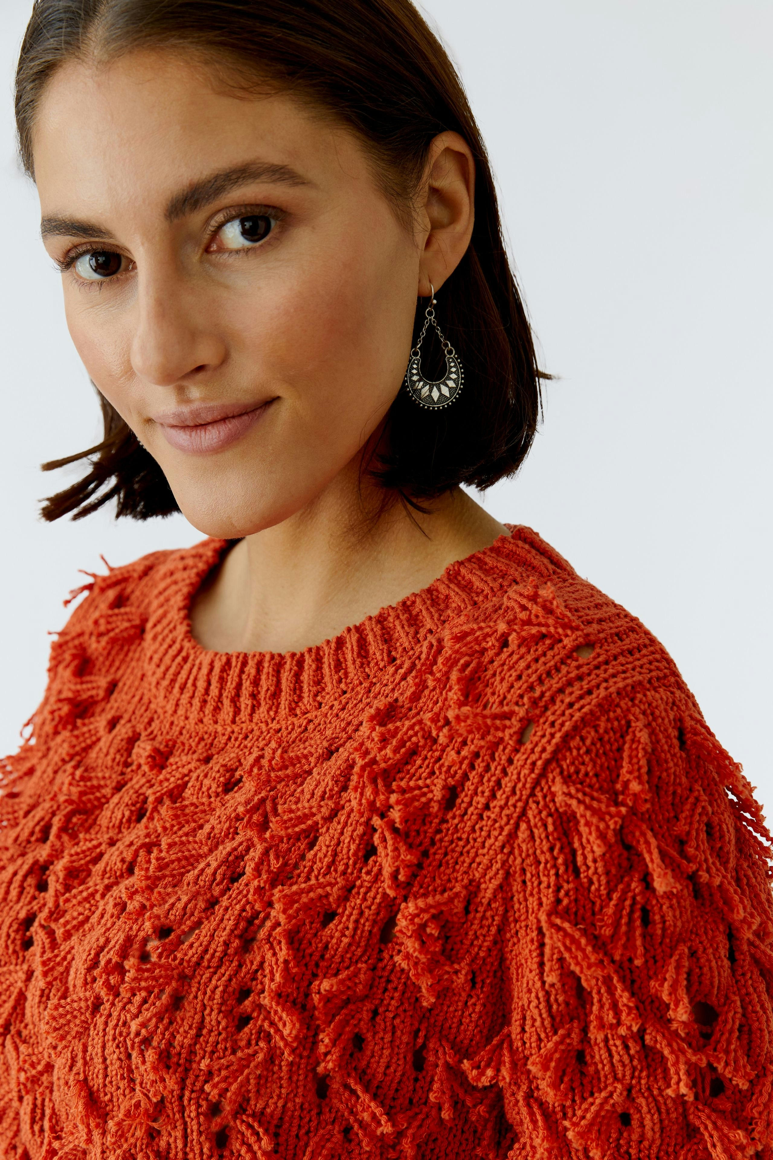 Damen-Pullover in leuchtendem Orange mit strukturiertem Muster, getragen von einer Frau.