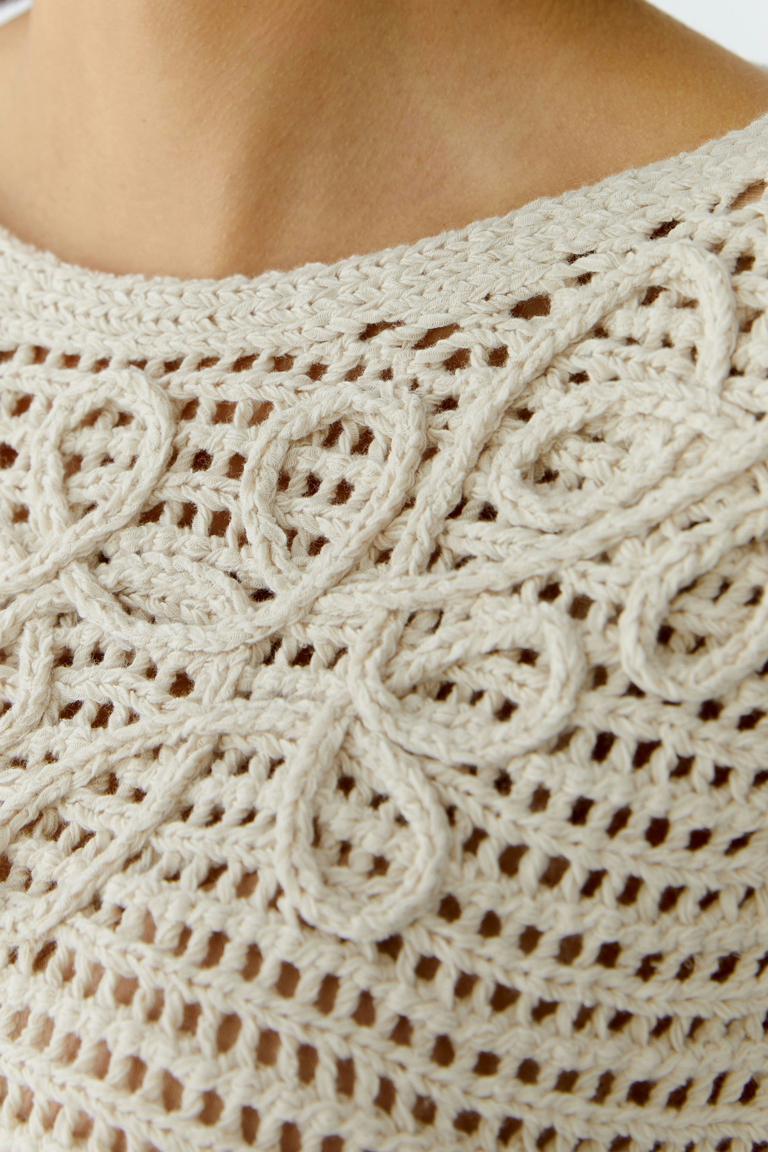 Helle Damen-Pullover: Detailaufnahme eines luftigen, gestrickten Pullovers mit floralem Muster.