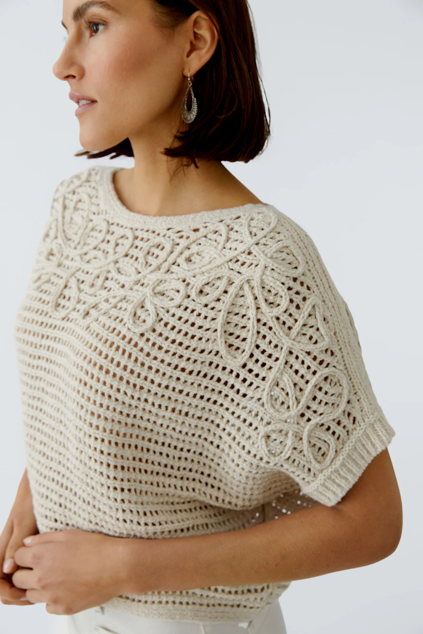 Casual women's pullover: A woman in a light knitted pullover with floral patterns, showcasing a relaxed style.