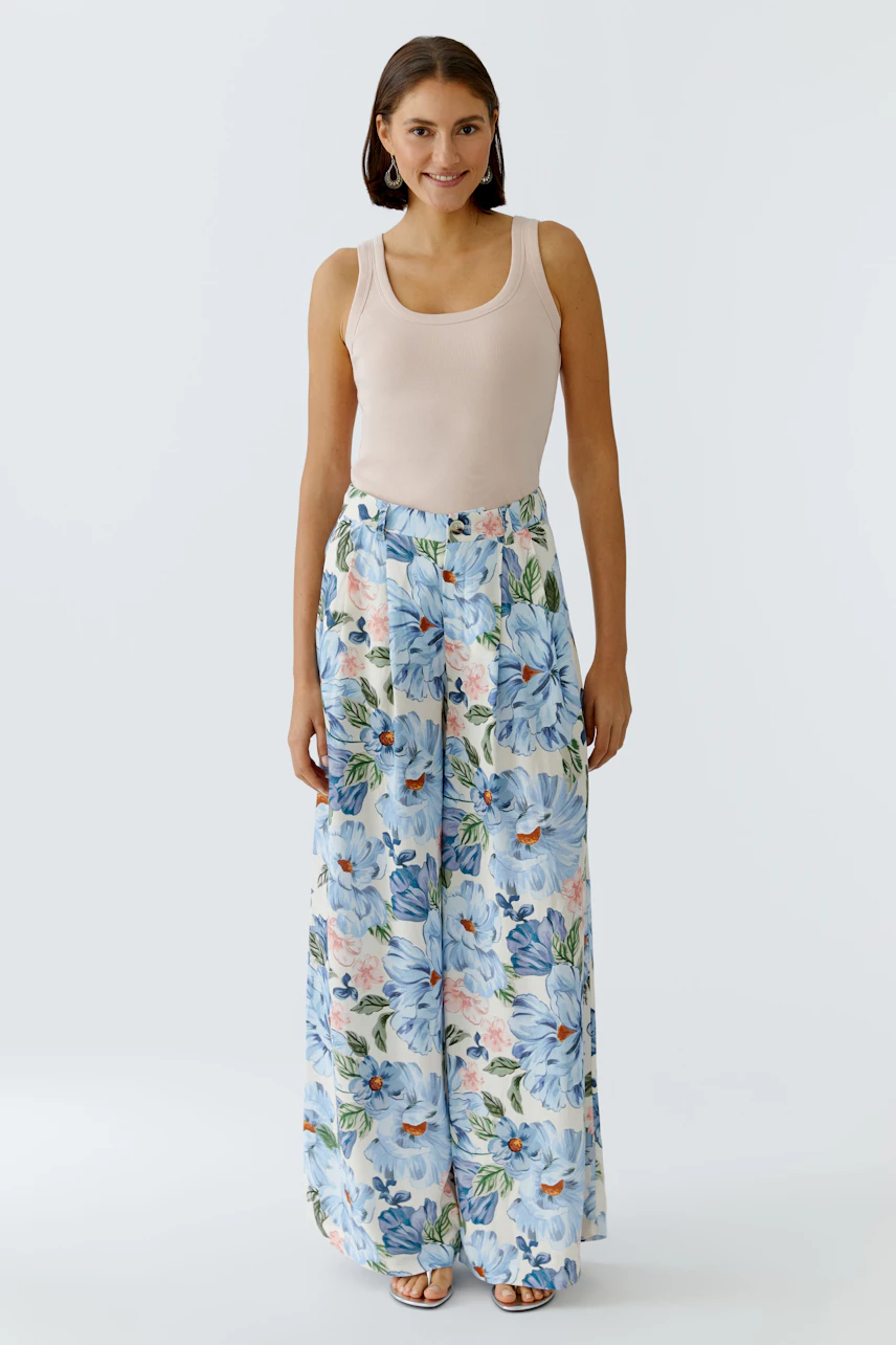 Casual women's tank top: A woman in a light tank top paired with floral wide-leg pants.