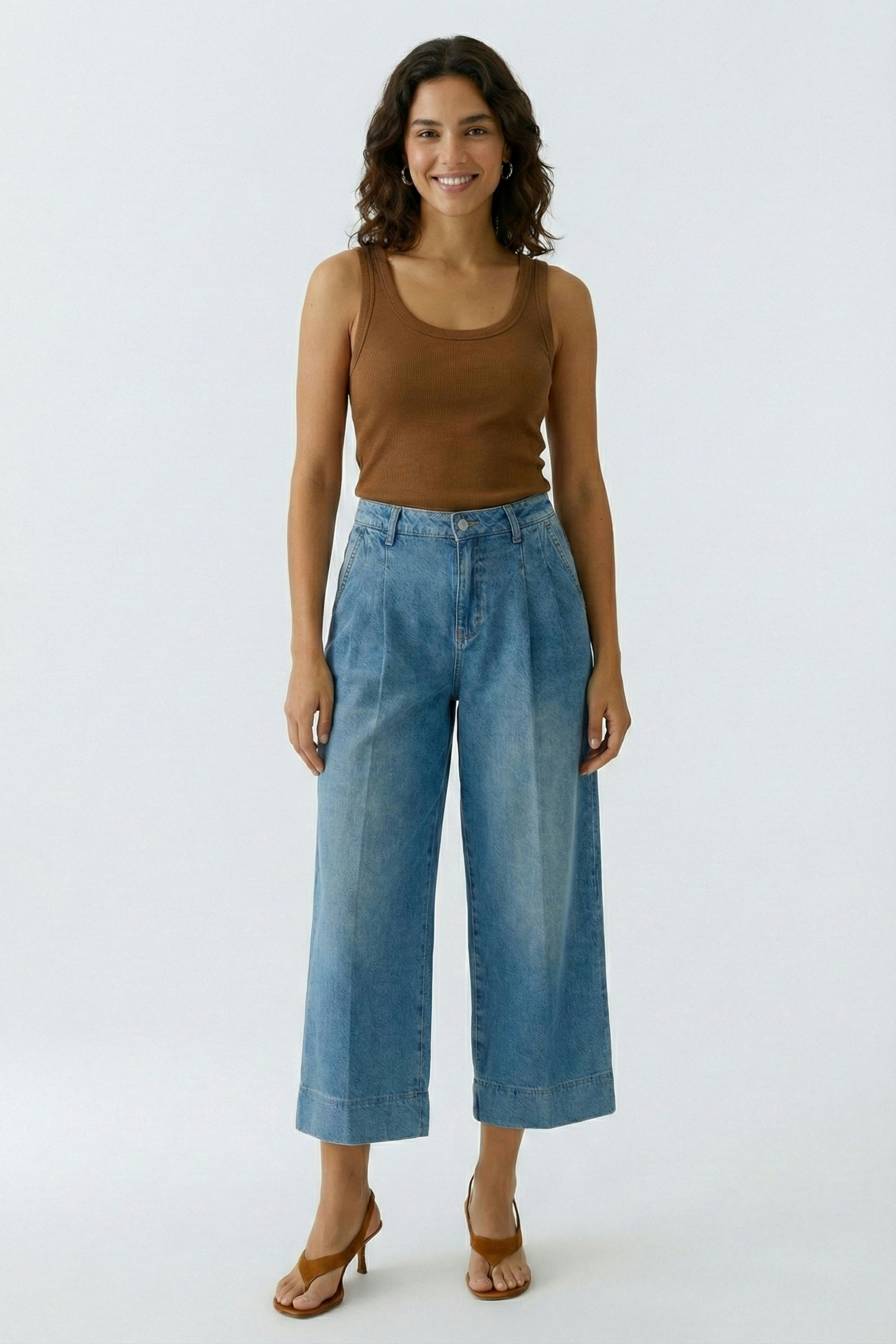 Beige Damen-Tank Top: Frau trägt ein schlichtes, ärmelloses Oberteil in Braun zu lässigen Jeans.