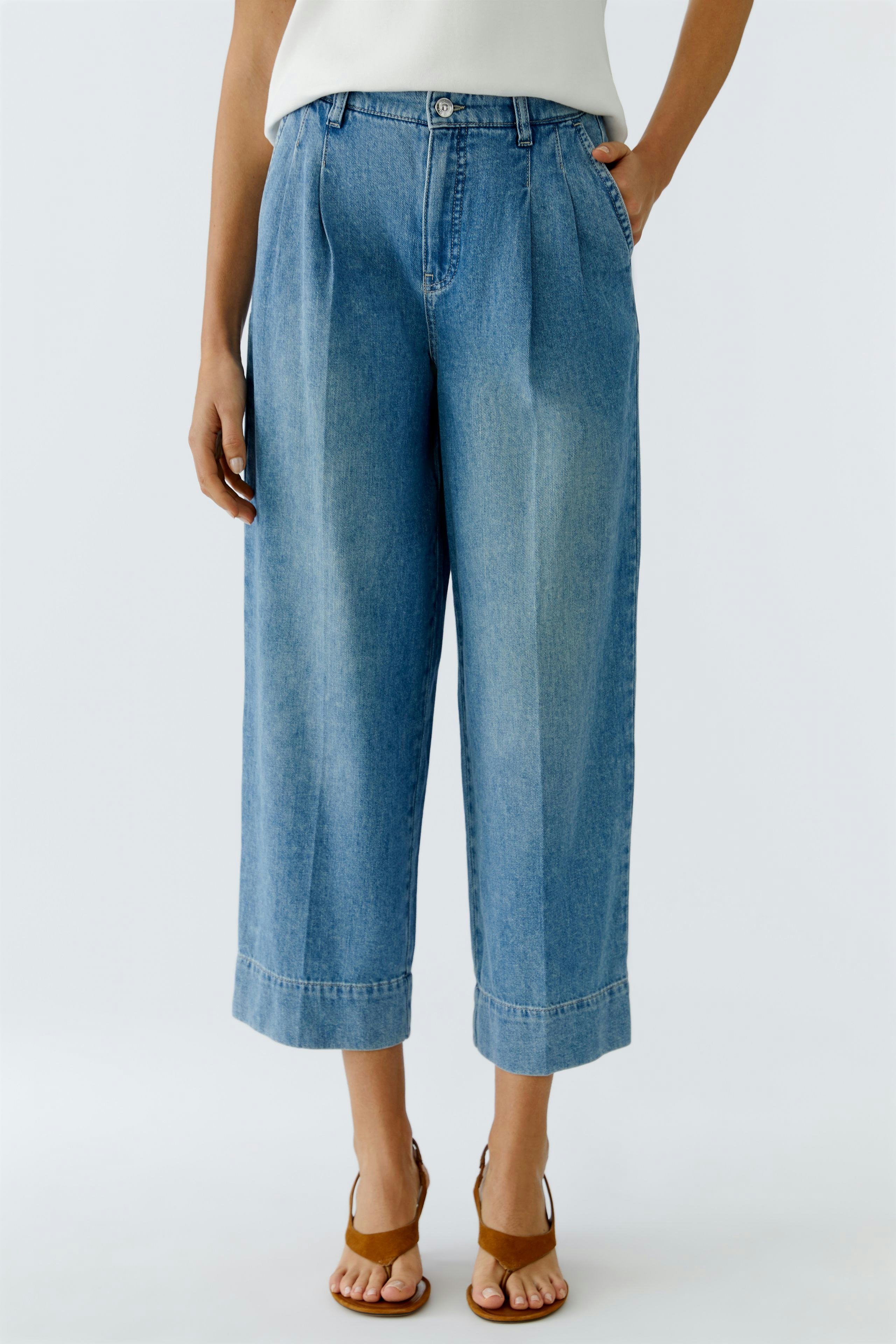 Bundfaltenhose: Frau trägt lässige, weite Jeans mit Bundfalten und umgeschlagenem Saum.