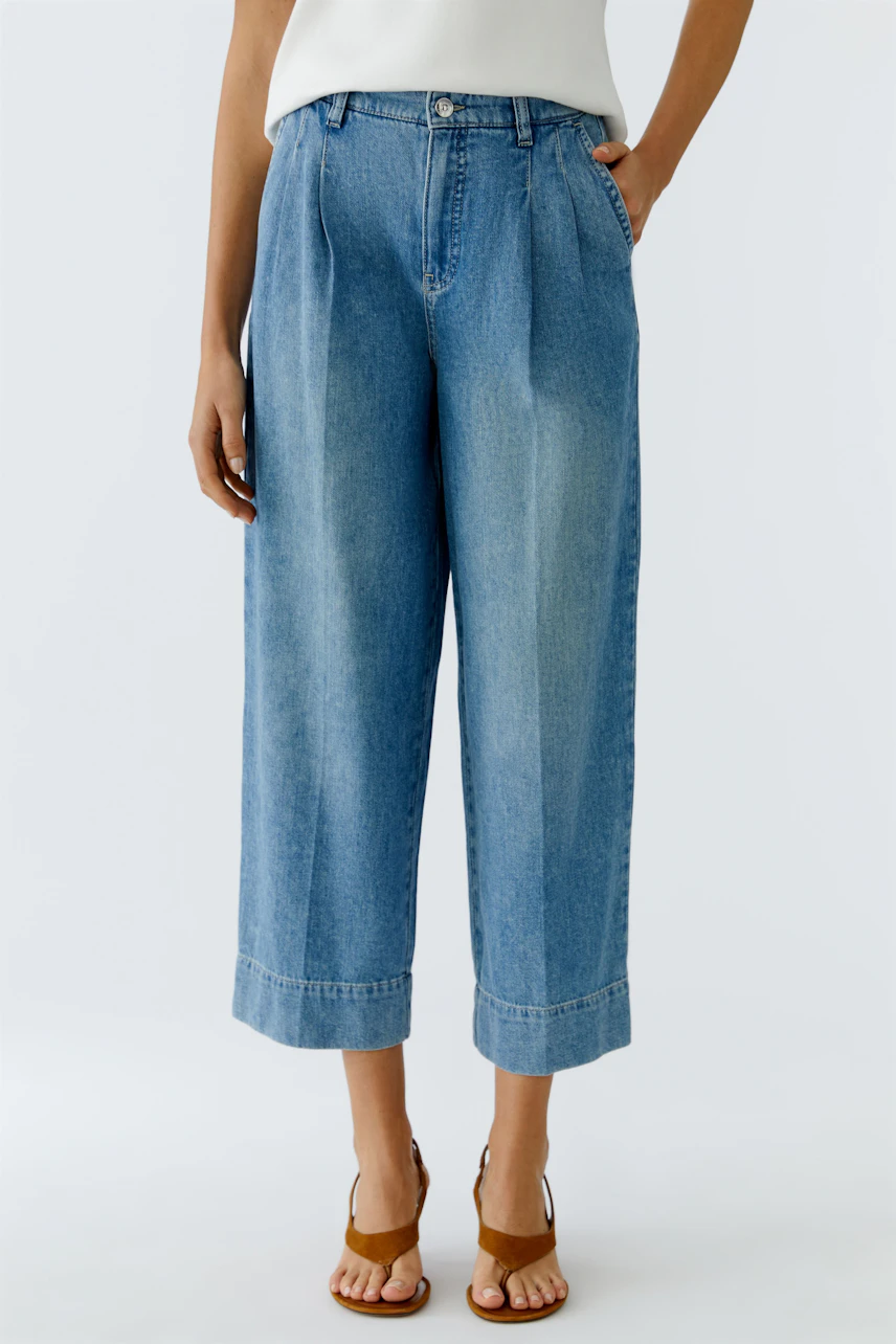 Casual women's pleated trousers: A woman in light blue, wide-leg pants with a relaxed fit.