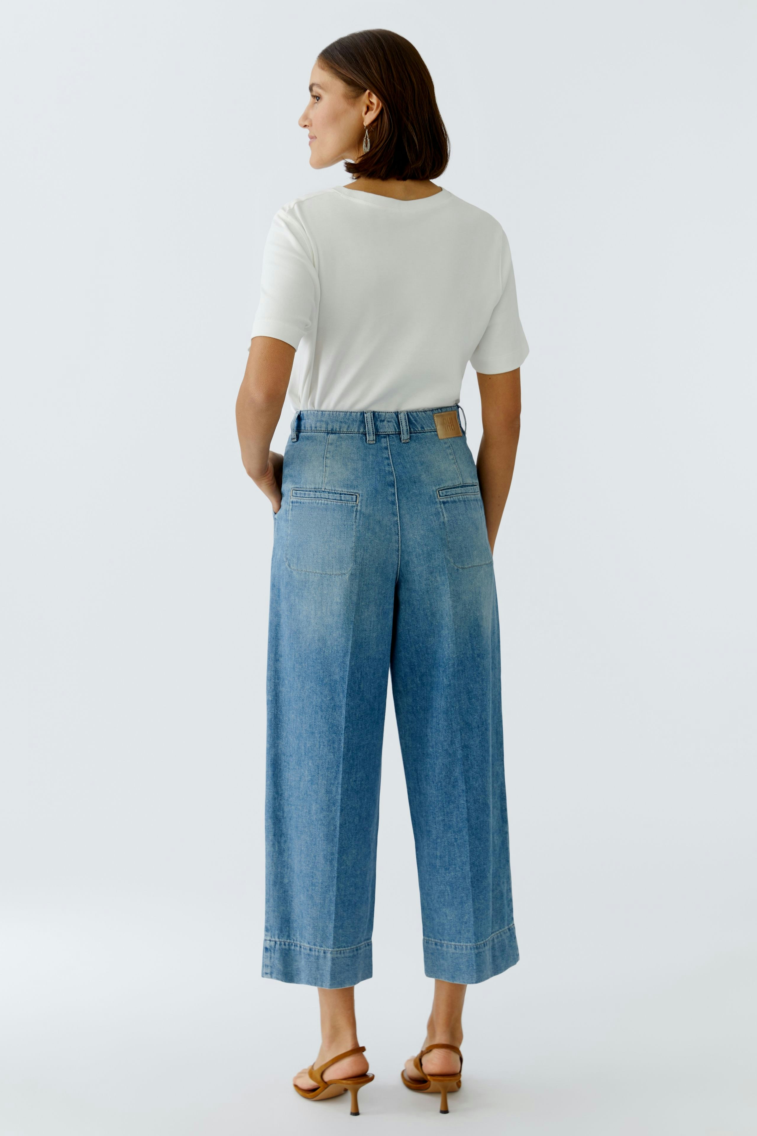 Bundfaltenhose: Frau trägt eine lässige, hellblaue Bundfaltenhose mit weitem Bein und T-Shirt.