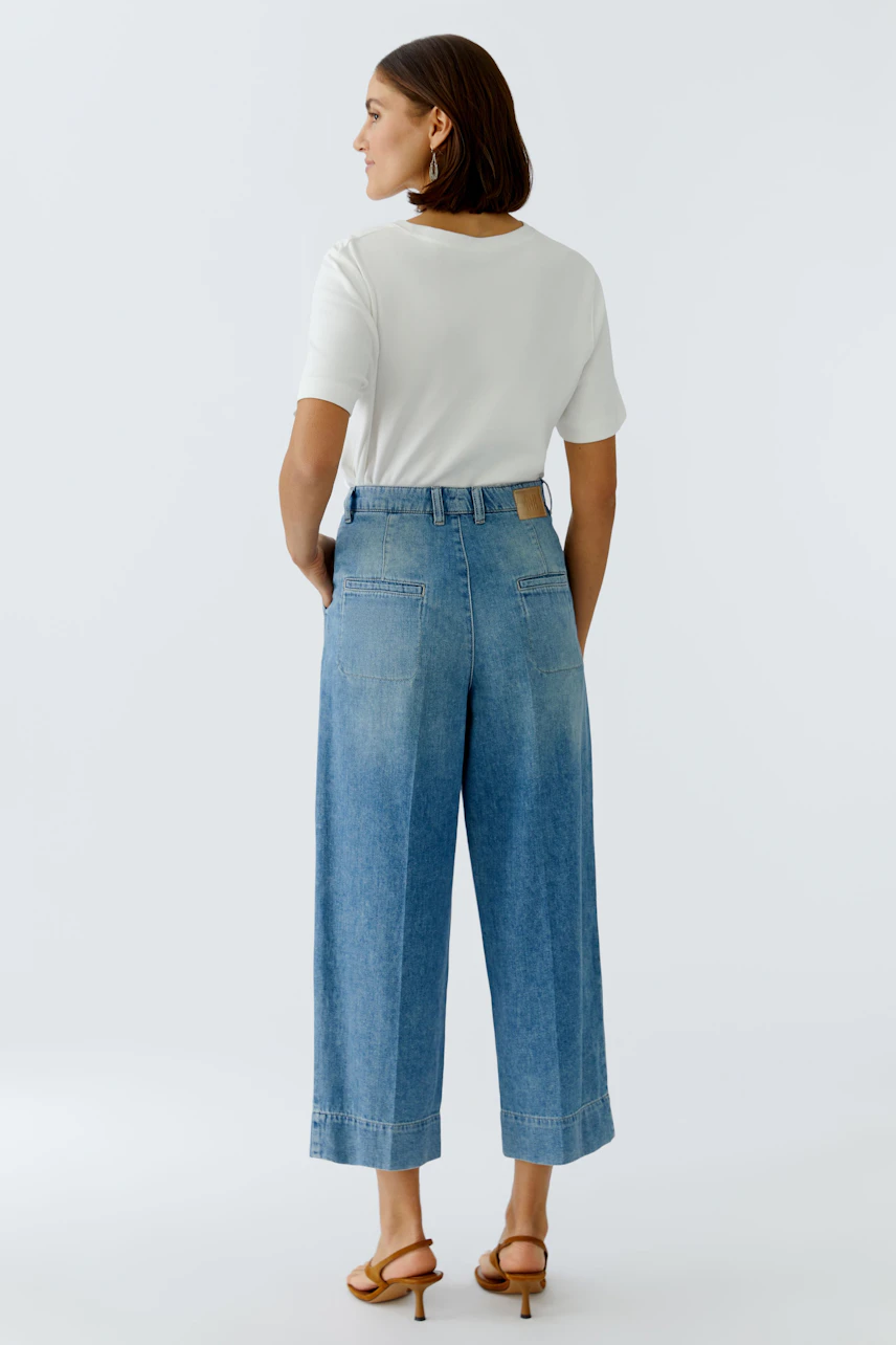 Casual women's pleated trousers: A woman in light blue pleated pants with a white top, showcasing a relaxed fit.