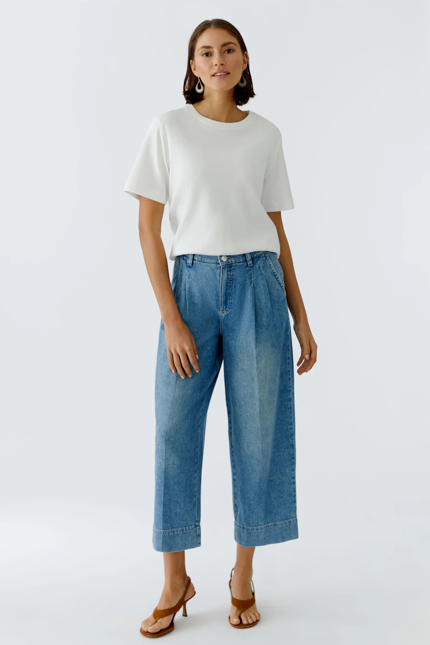 Casual women's pleated trousers: A woman in light blue pleated trousers and a white top stands confidently.