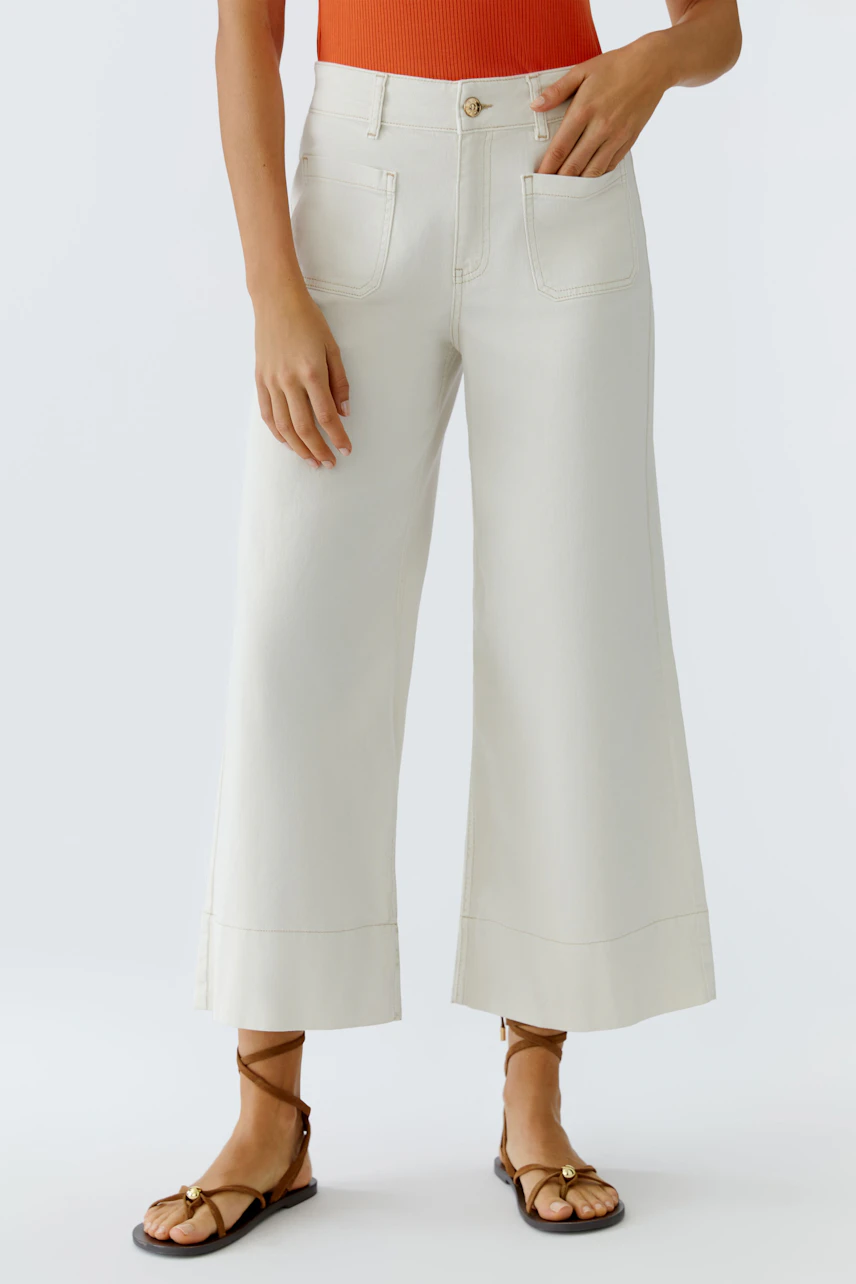Wide leg jeans: Woman wearing light-colored wide leg jeans with a fitted top and sandals.