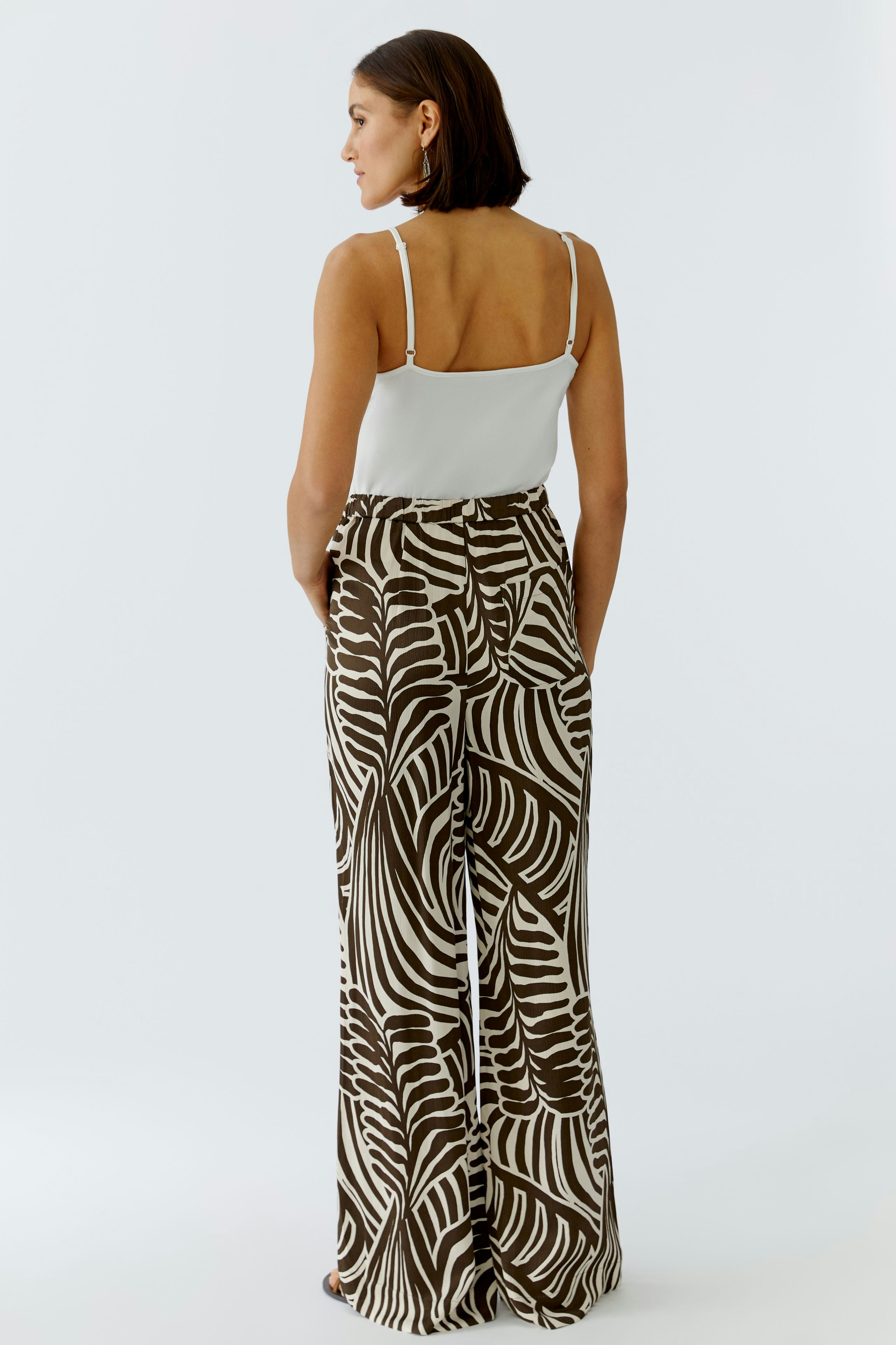 Bequeme Damen-Hose: Frau in weit geschnittener Hose mit auffälligem Muster und lässigem Top von hinten.