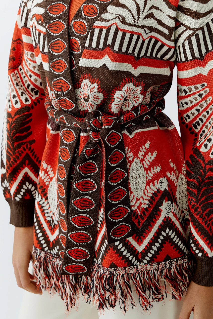 Colorful women's cardigan with a belt and fringe details, featuring a bold pattern.