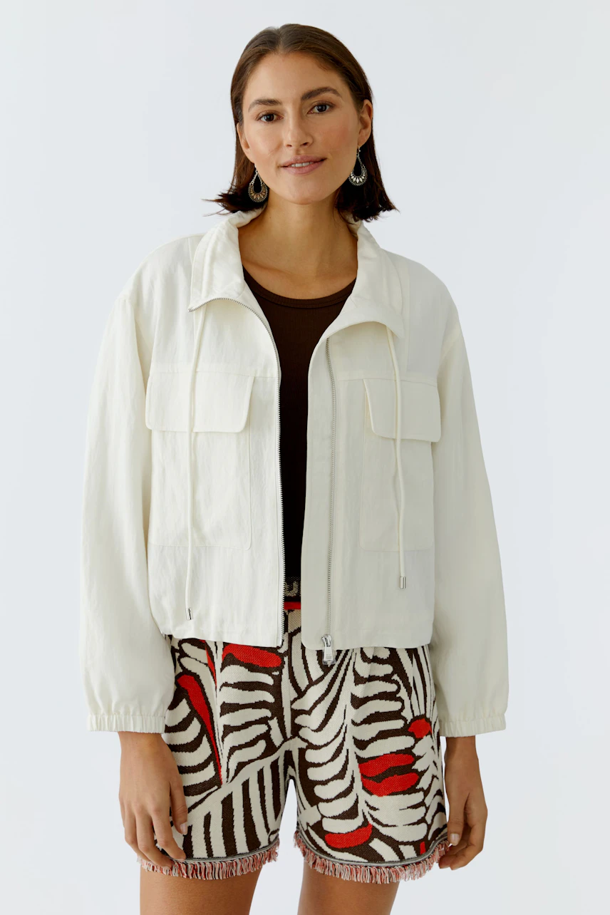 Casual women's blouson: A woman in a light jacket with pockets, paired with patterned shorts.