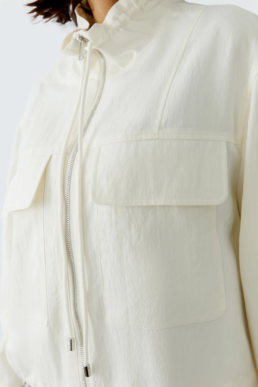 Casual women's blouson: A woman in a light cream jacket with a zip and two front pockets.