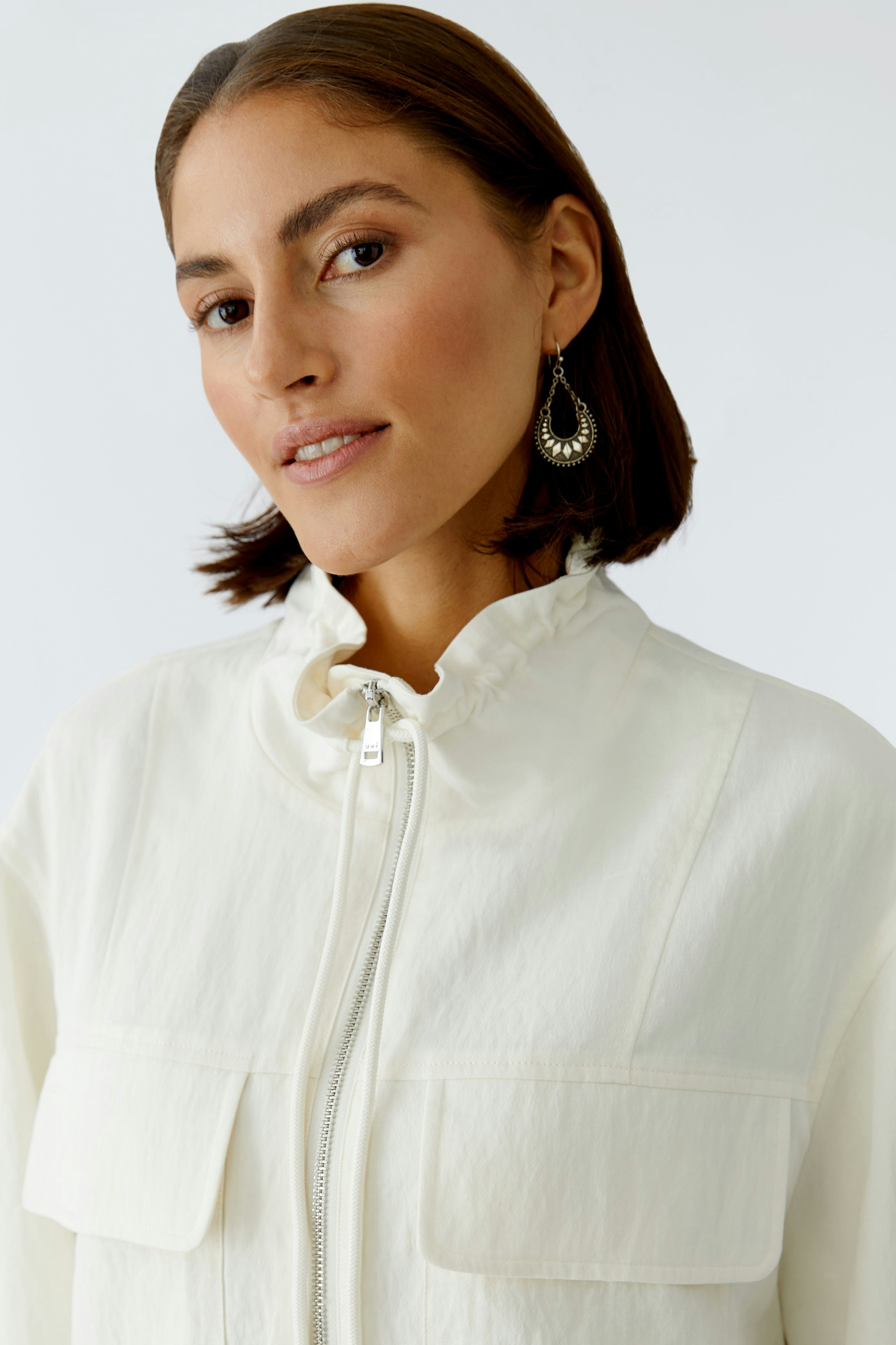 Damen-Blouson: Frau in hellem Blouson mit Stehkragen und praktischen Taschen, lässiger Look.