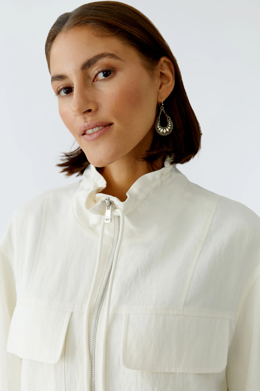 Casual women's blouson: Woman in a light jacket with a high collar and pockets, looking confidently.