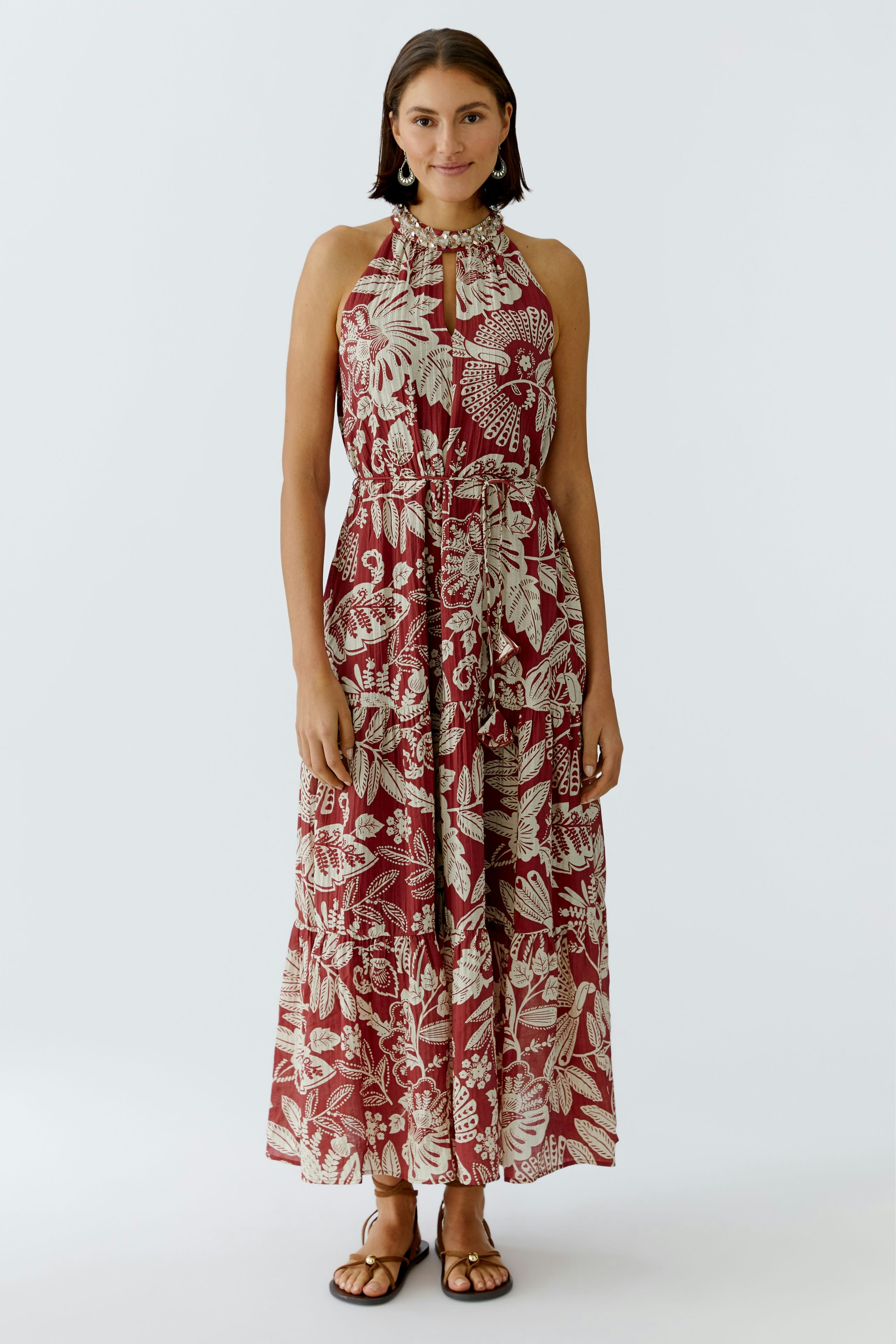 Maxikleid: Frau in einem rot-weißen, gemusterten Maxikleid mit halbem Reißverschluss und lockerer Passform.