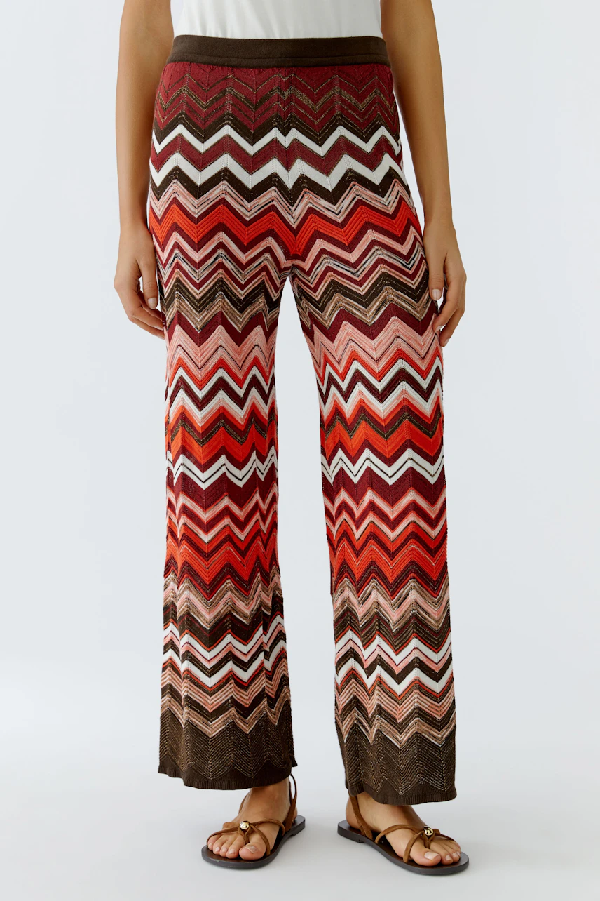 Colorful knit pants: Woman in vibrant zigzag patterned knit pants, standing confidently.