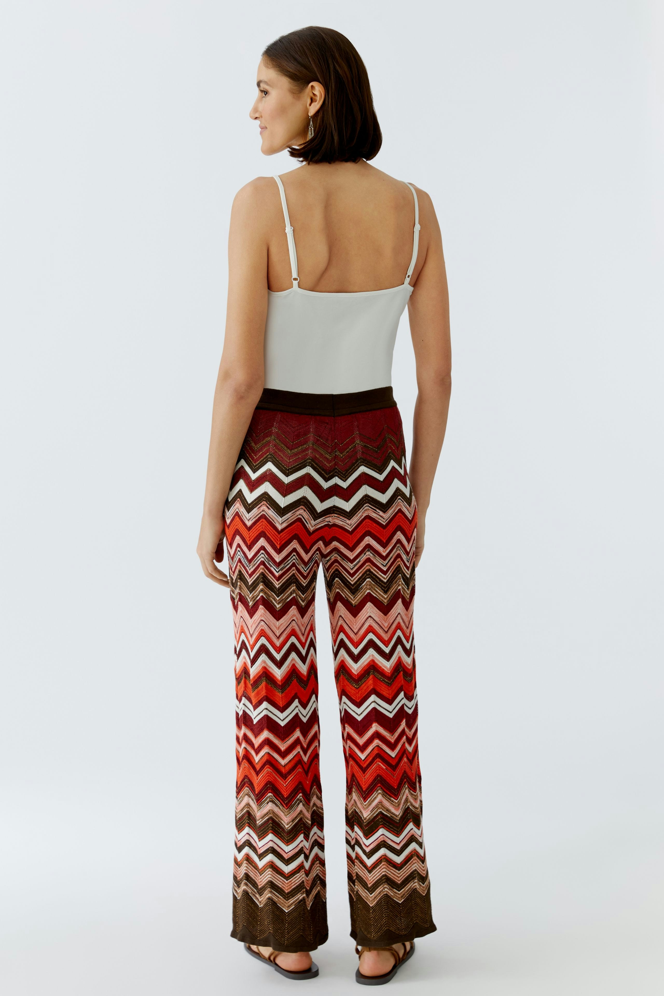 Bunte Damen-Strickhose: Frau mit bunten, gestreiften Strickhosen und schlichten Oberteil von hinten.