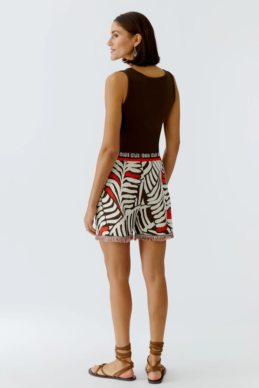 Casual women's shorts: A woman in patterned shorts with a fitted top, showcasing a relaxed summer look.
