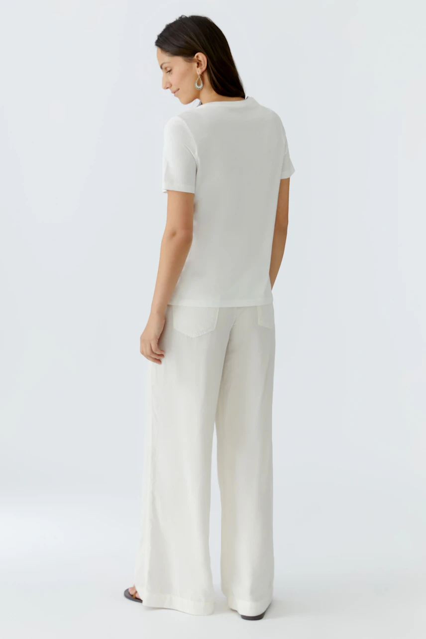 Casual women's T-shirt: A woman in a white short-sleeve top paired with light wide-leg pants.