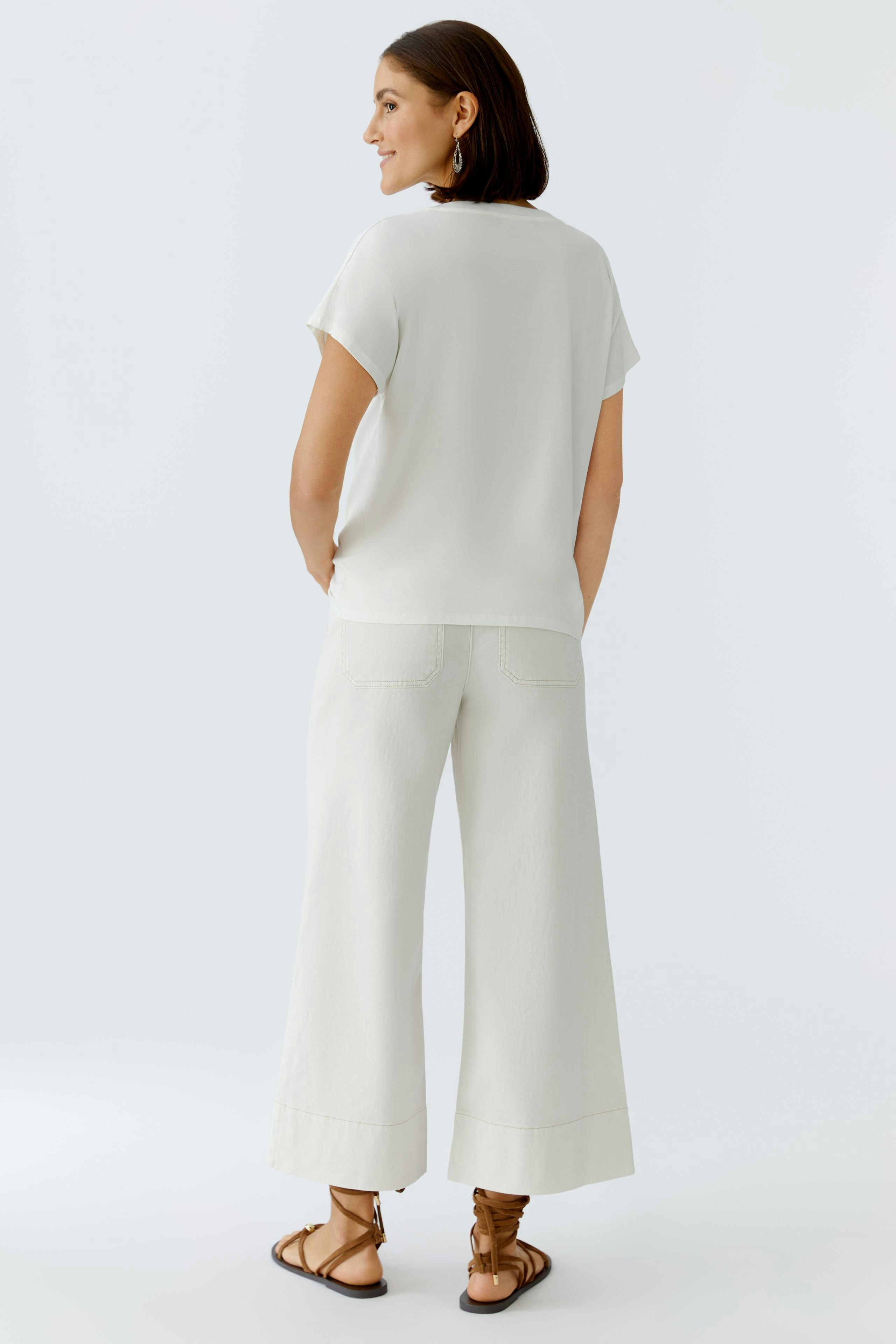 Bequeme Damen-T-Shirt: Frau in einem hellen T-Shirt mit kurzen Ärmeln und lässiger Passform von hinten.