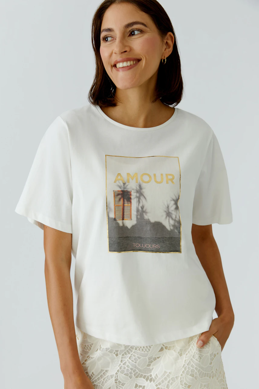 Casual women's T-shirt: Smiling woman in a white tee with a graphic print, perfect for everyday wear.