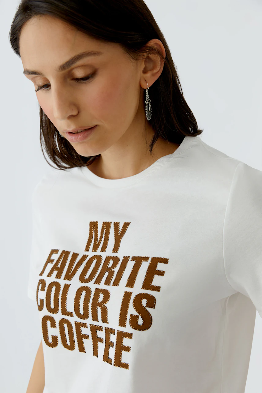 Casual women's T-shirt: Woman in a white tee with 'My favorite color is coffee' printed in brown.