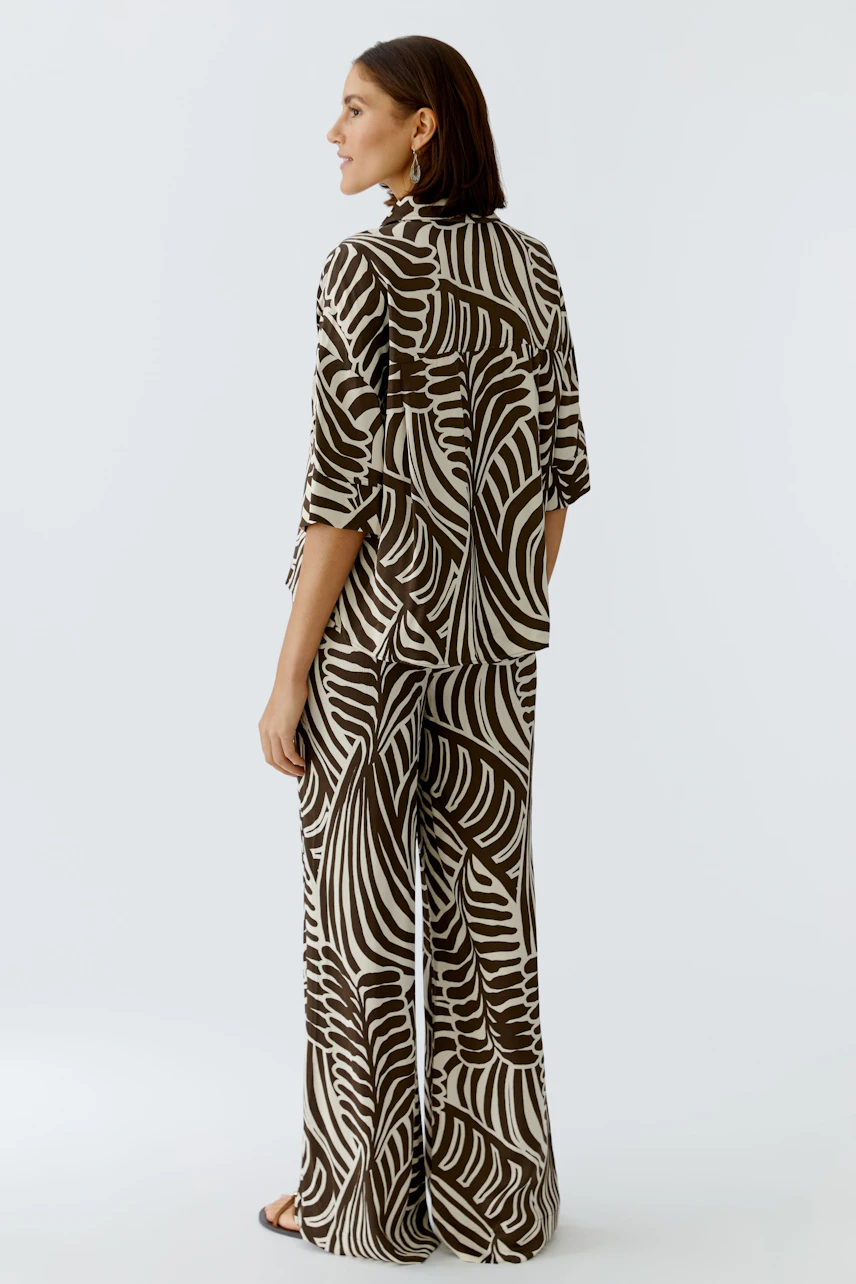 Casual women's blouse: A woman in a patterned blouse and matching pants, showcasing a relaxed style.