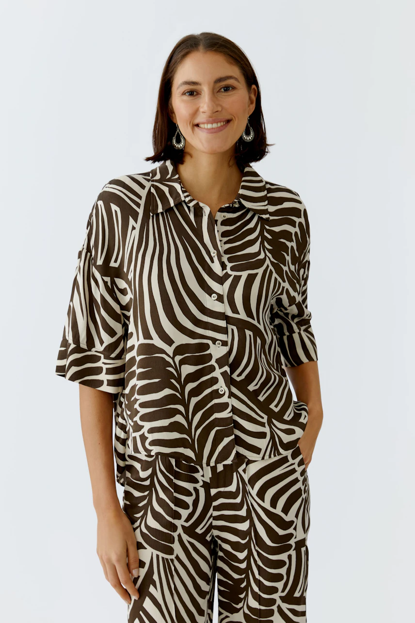 Casual women's blouse: A woman in a brown and cream striped blouse with a relaxed fit.