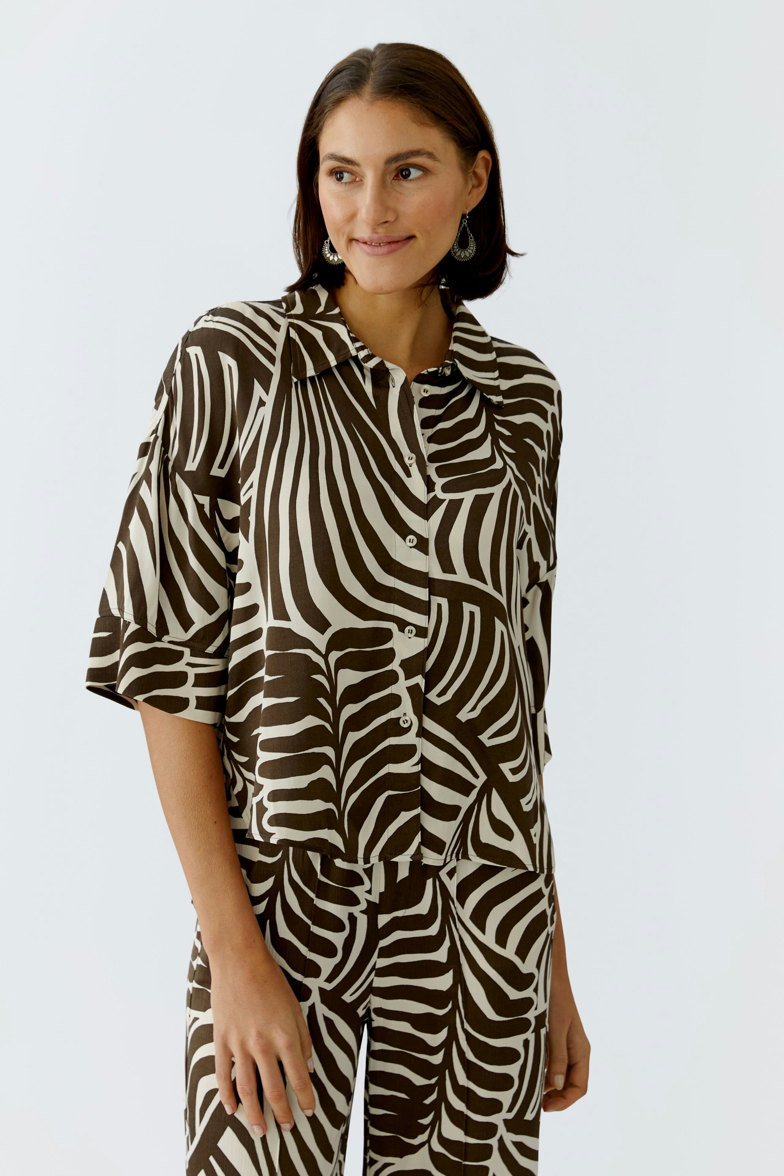 Damen-Bluse: Frau in brauner Bluse mit Zebra-Muster und lässigem Schnitt lächelt freundlich.