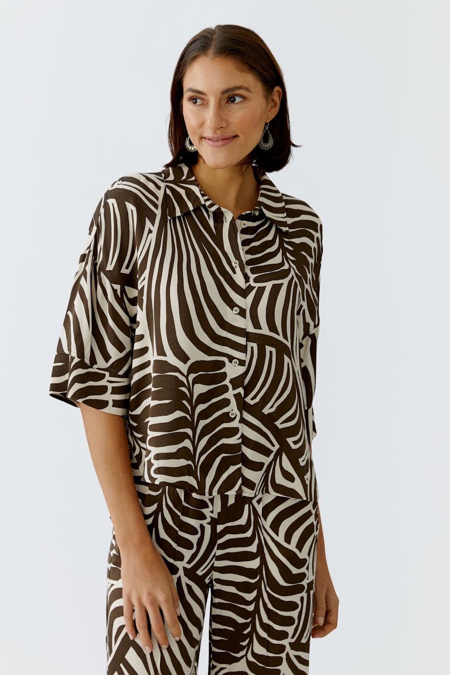 Casual women's blouse: Brown and white patterned blouse with a relaxed fit and short sleeves.