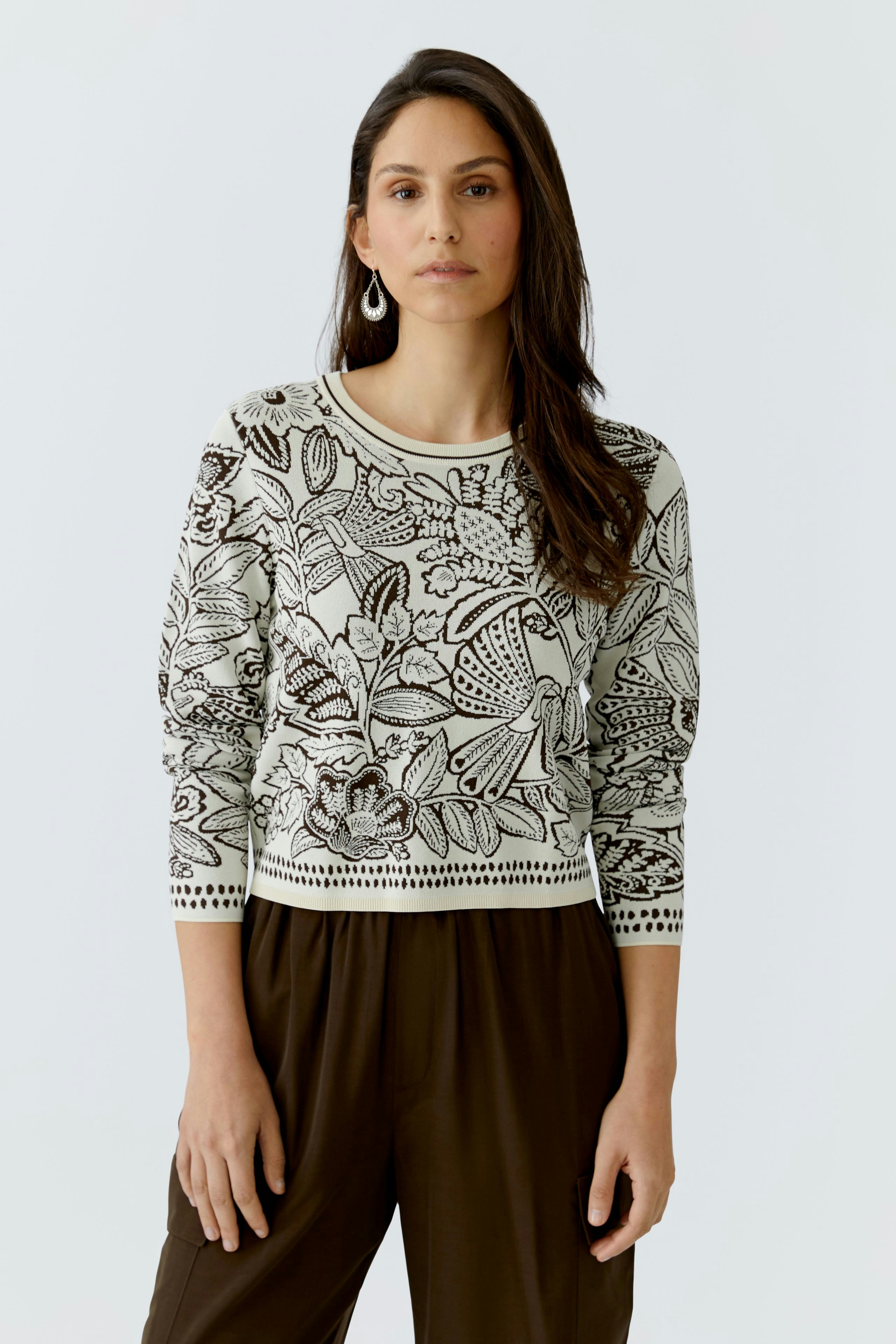 Damen-Pullover: Frau trägt einen gemusterten Pullover mit floralen Motiven und lässiger Passform.
