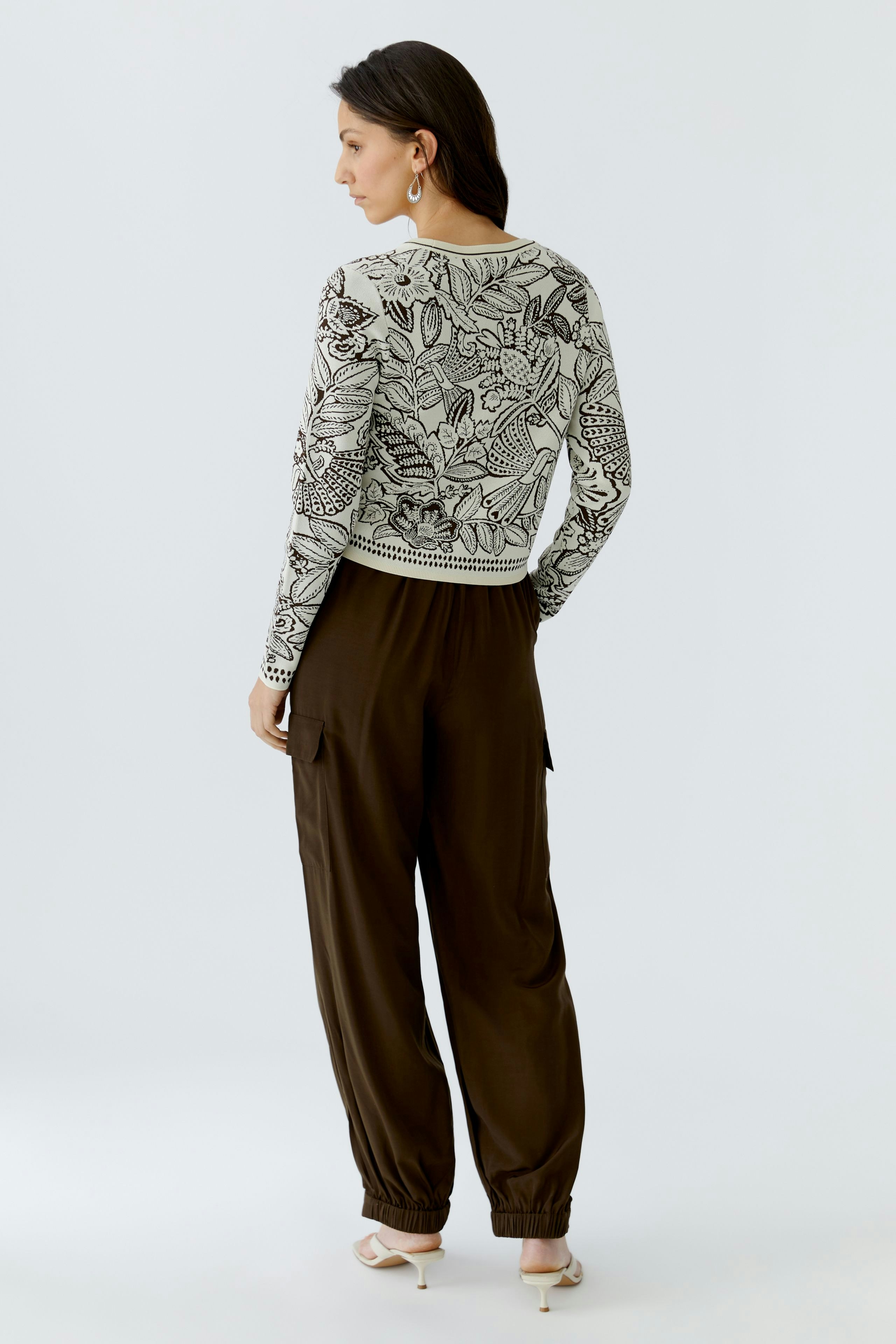 Damen-Pullover mit floralem Muster: Frau trägt einen bequemen, lässigen Pullover in Kombination mit lockeren Hosen.