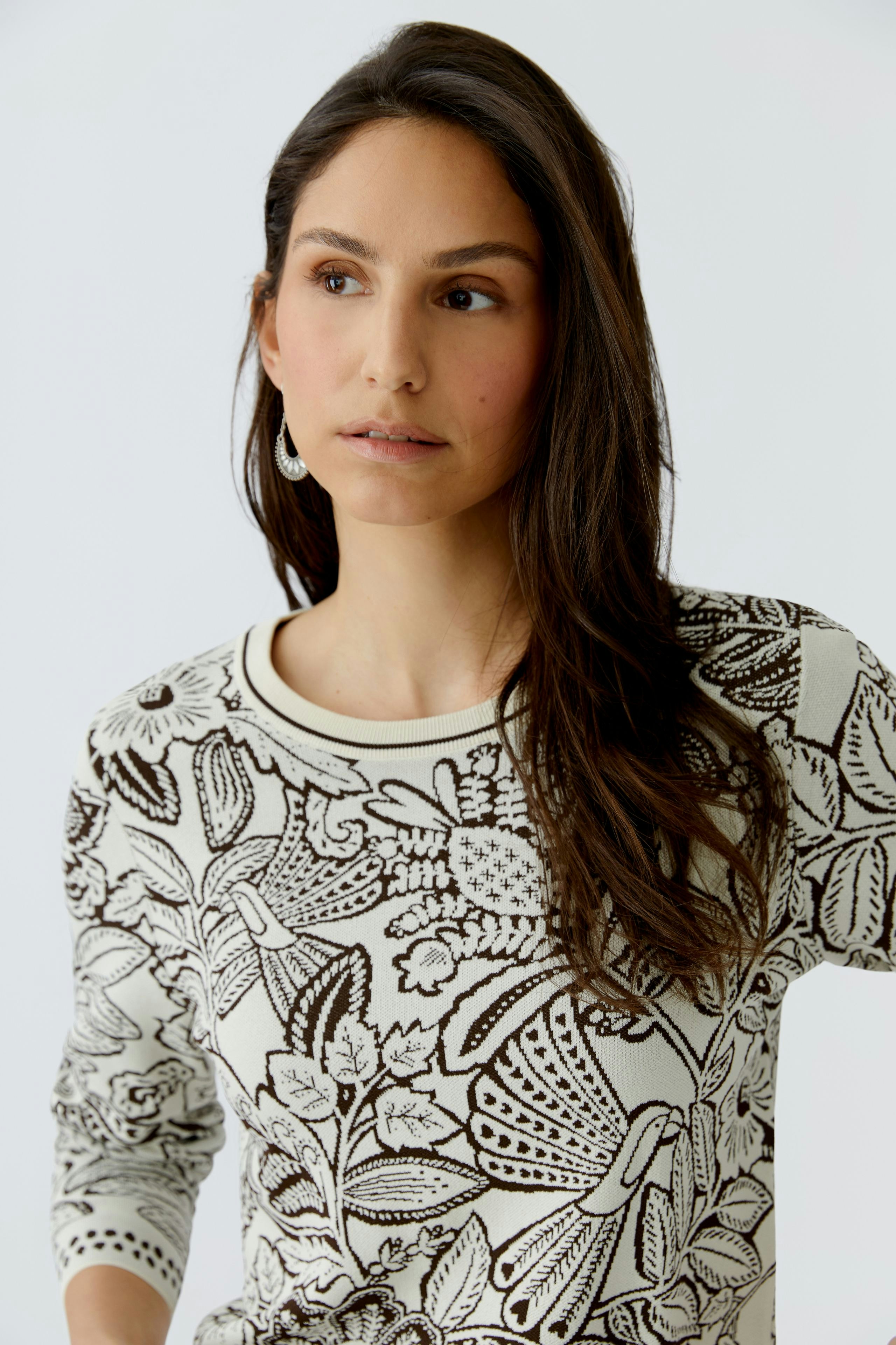 Damen-Pullover: Frau in einem cremefarbenen Pullover mit floralem Muster, lässig und modern.
