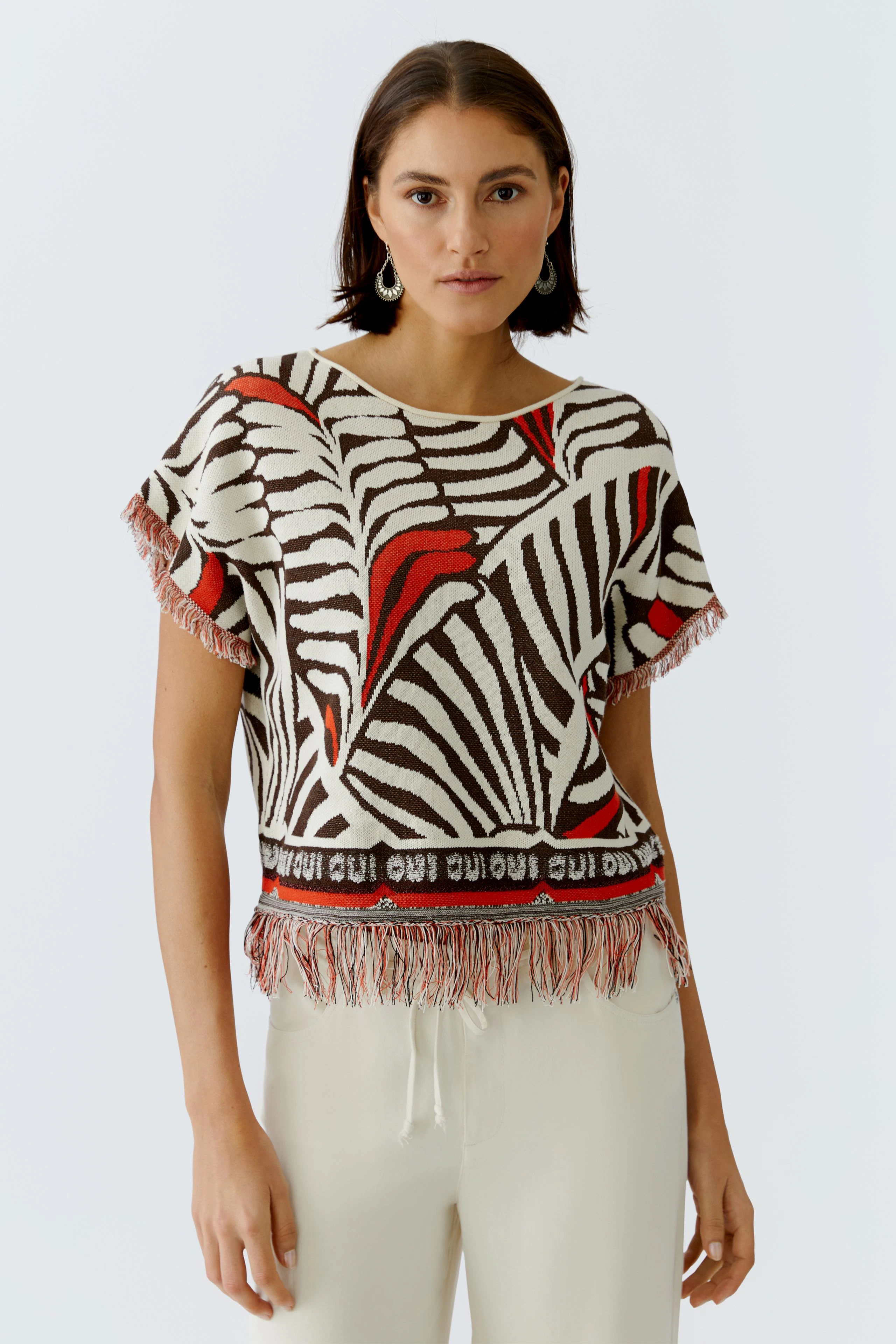 Damen-Pullover mit auffälligem Zebra-Muster und Fransen, lässig kombiniert mit hellen Hosen.
