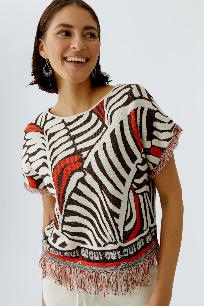 Damen-Pullover mit auffälligem Zebra-Muster und Fransen, lässig getragen von einer Frau.