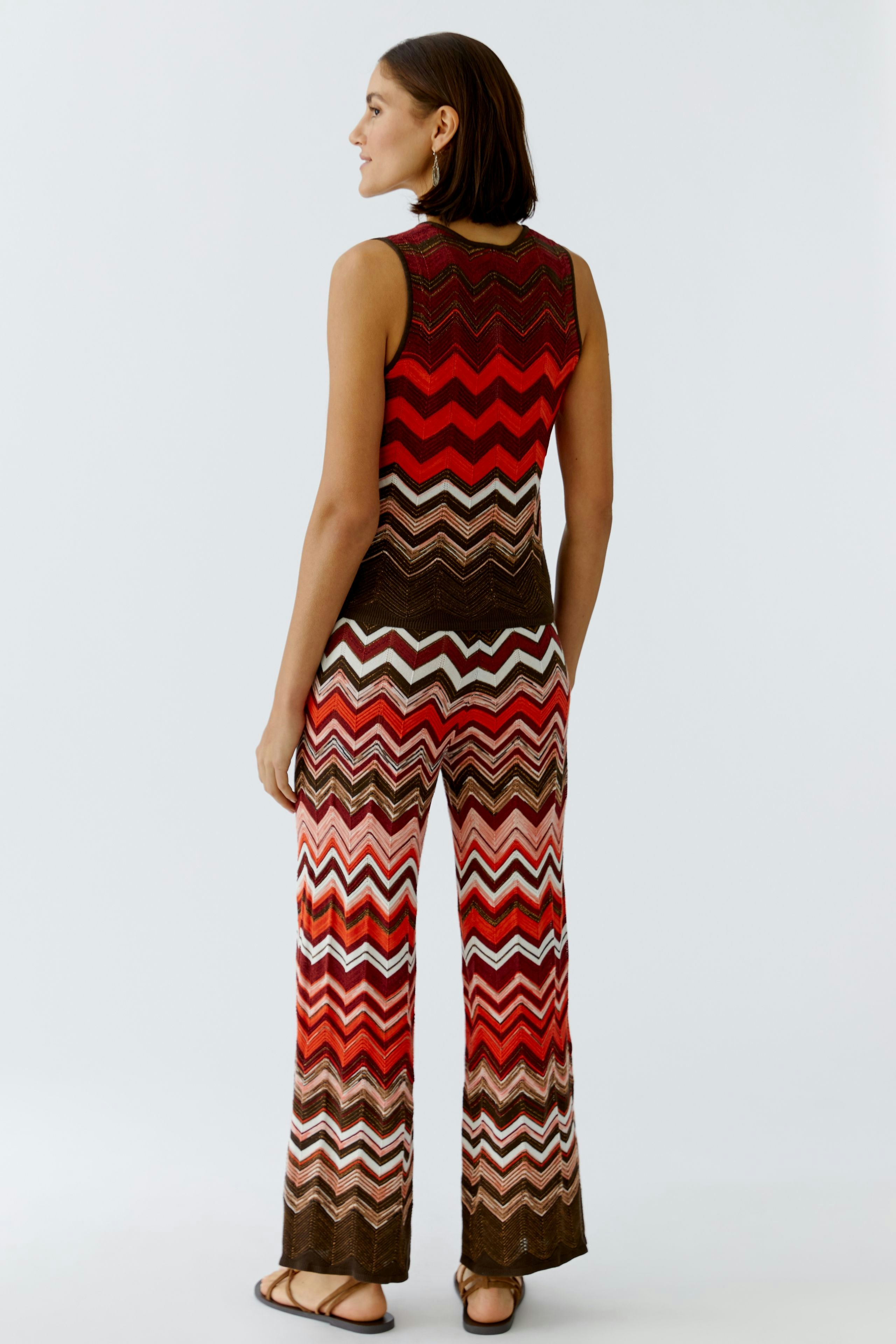 Bunt gestreiftes Damen-Top: Frau in ärmellosem Oberteil mit Wellenmuster und lässiger Hose.