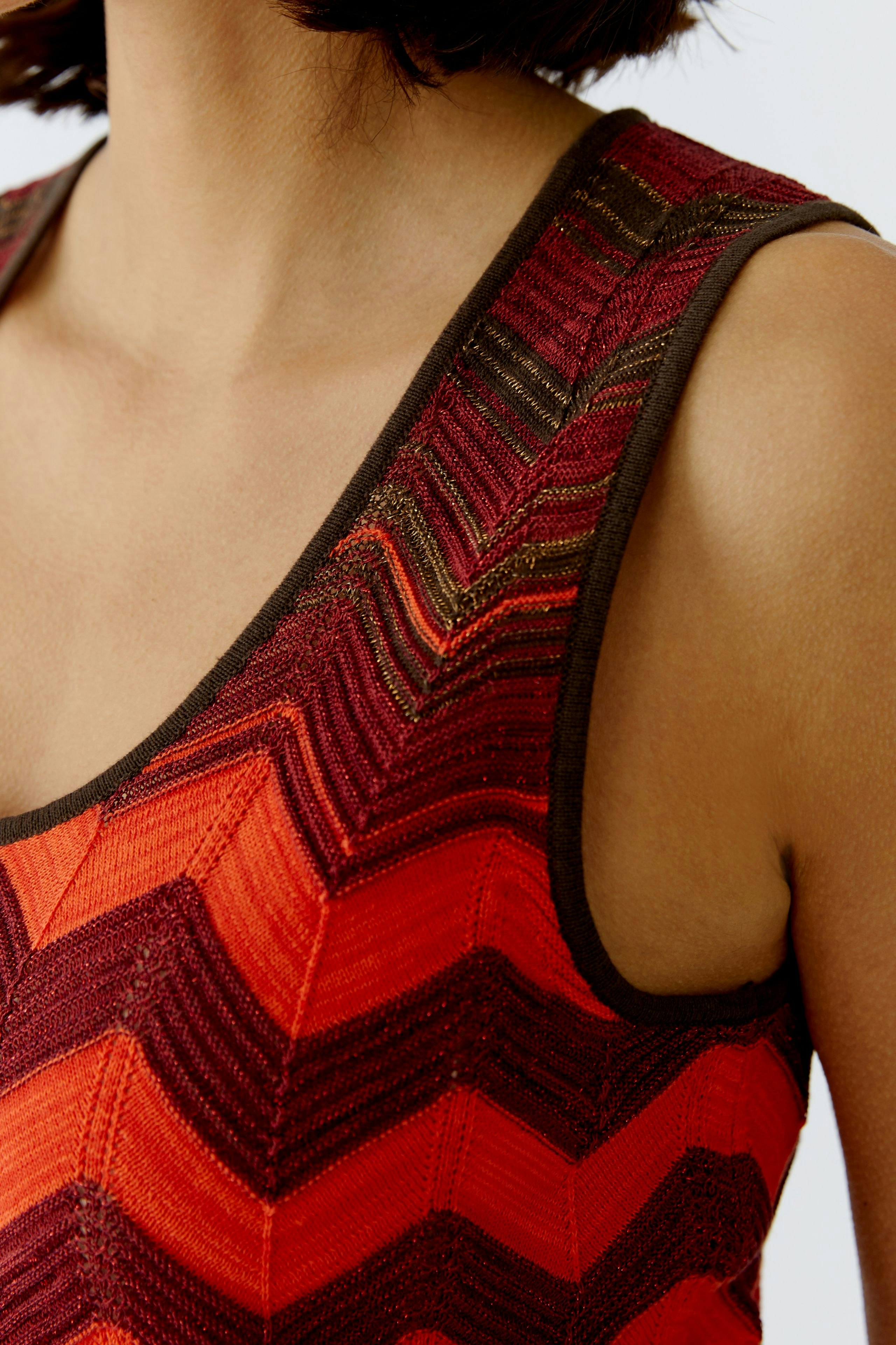 Damen-Top: Frau trägt ein rotes, gestreiftes Top mit Wellenmuster und breiten Trägern.