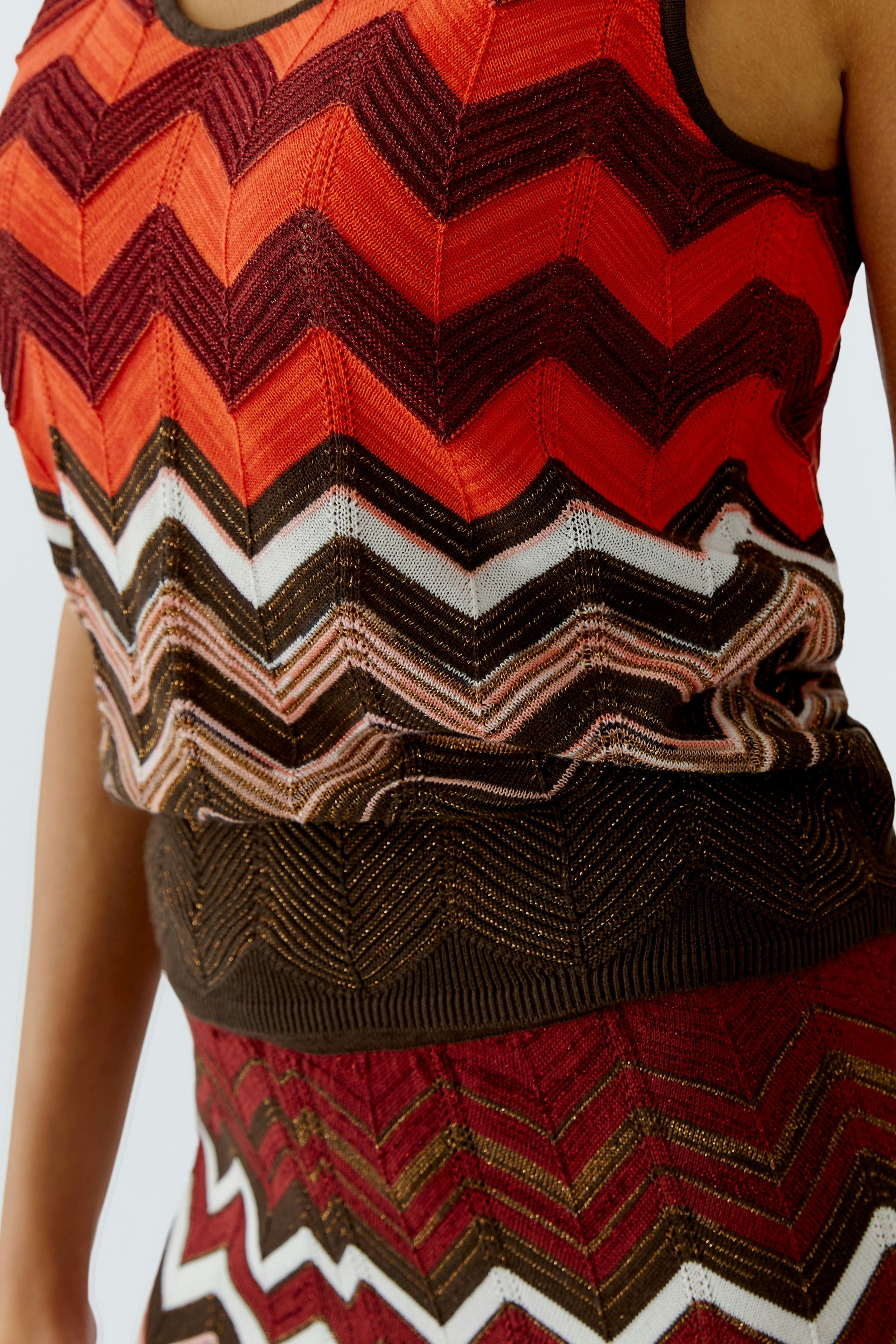 Damen-Top: Frau trägt ein farbenfrohes, gestreiftes Top mit Wellenmuster in Rot- und Brauntönen.