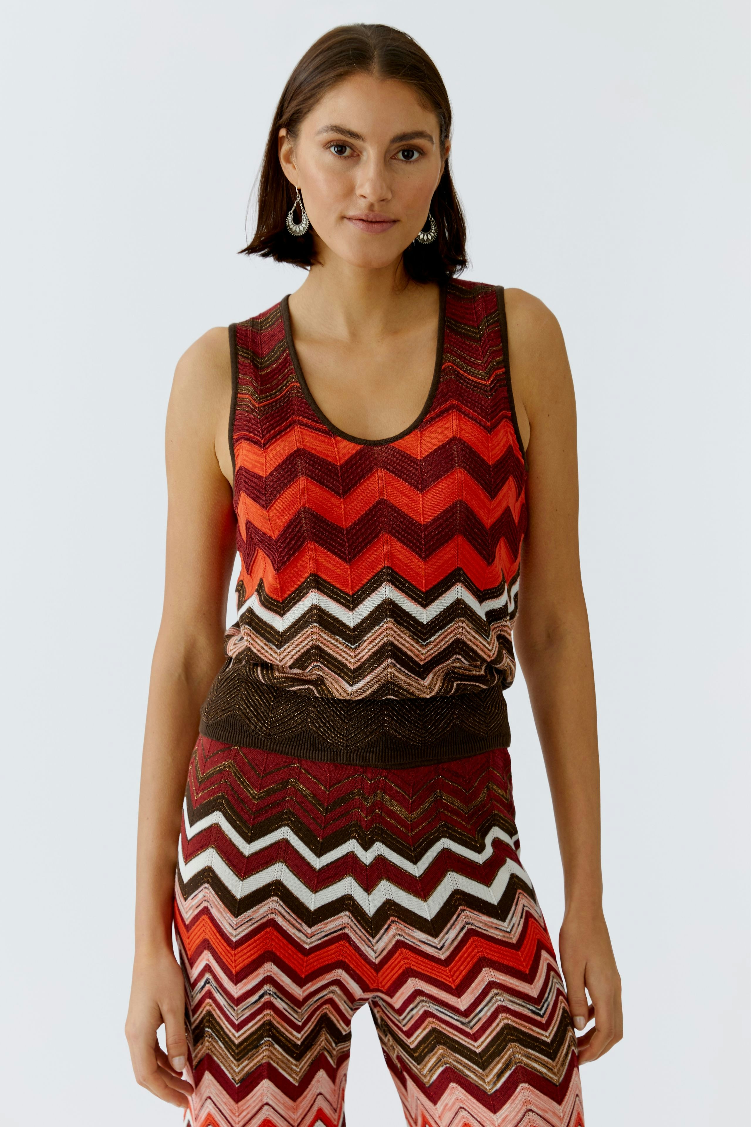 Buntes Damen-Top: Frau trägt ein ärmelloses, gestreiftes Top in warmen Farben.