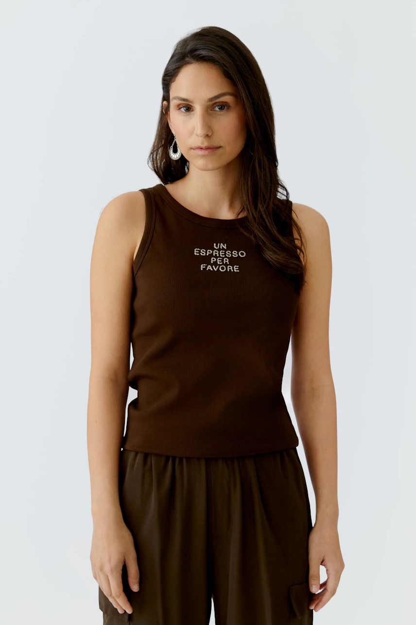 Casual women's tank top: A woman in a brown tank top with a printed design, paired with relaxed pants.