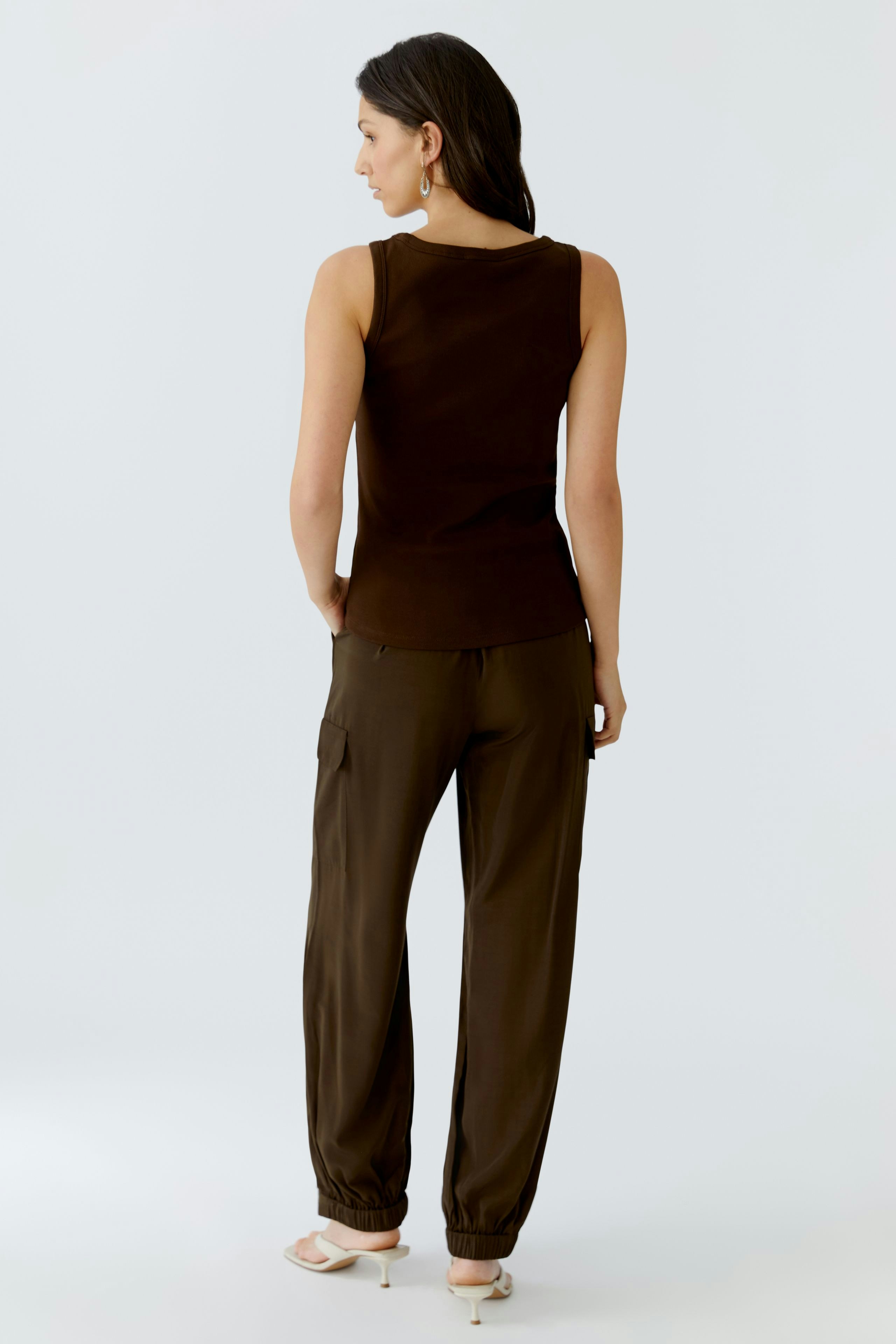 Damen Tank Top: Frau trägt ein braunes, ärmelloses Top mit lässiger Passform und kombiniert es mit bequemen Hosen.
