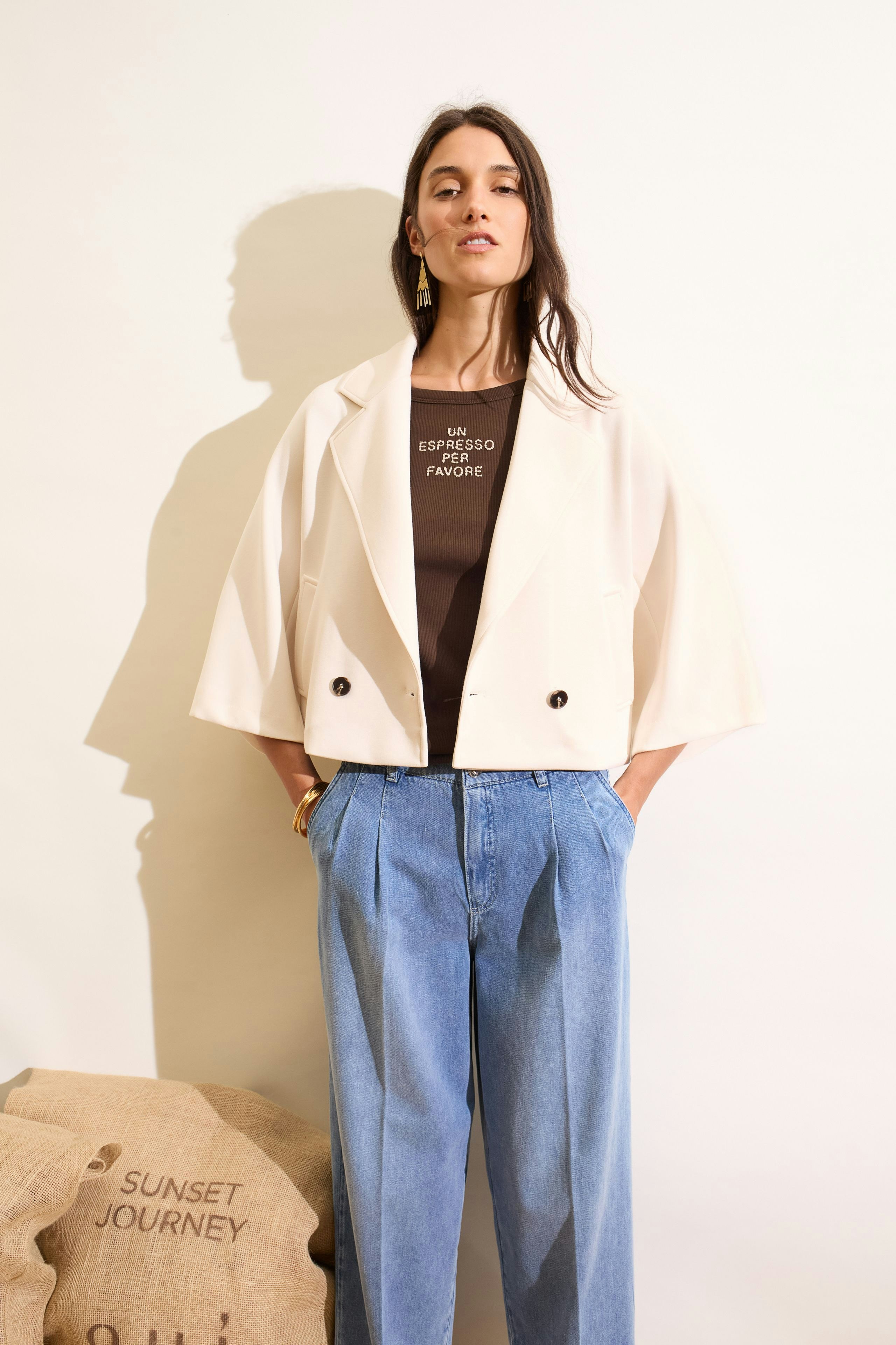 Casual tank top: Woman in brown tank top under a cream jacket, paired with relaxed blue jeans.